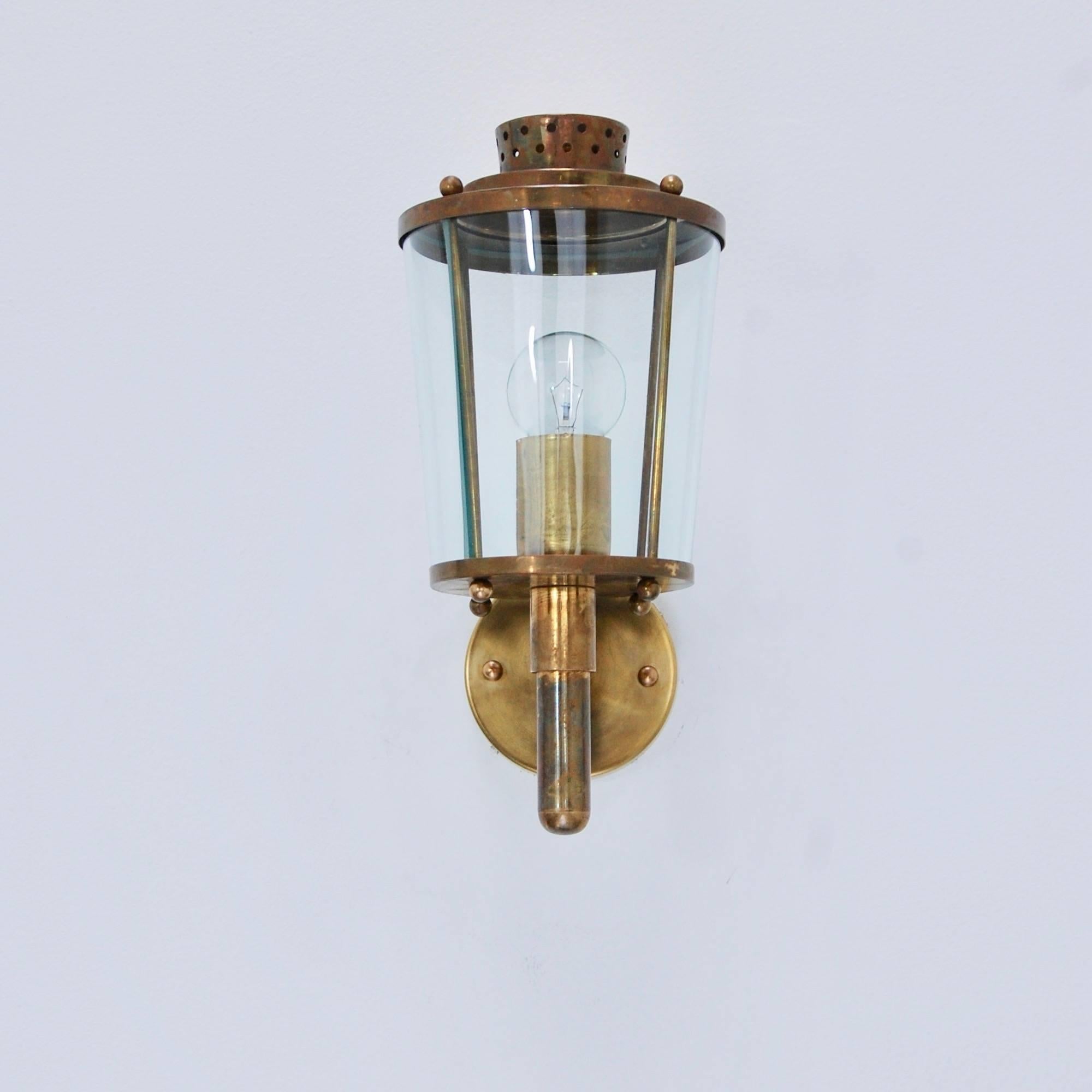 A pair of Italian indoor/outdoor wall lanterns from of the period 1950s Italy. Partially restored, patina lacquered brass finish with a single E12 based socket per glass cylinder shade. Maximum wattage 40-60 watts per socket. Back plate has 2 ¾”