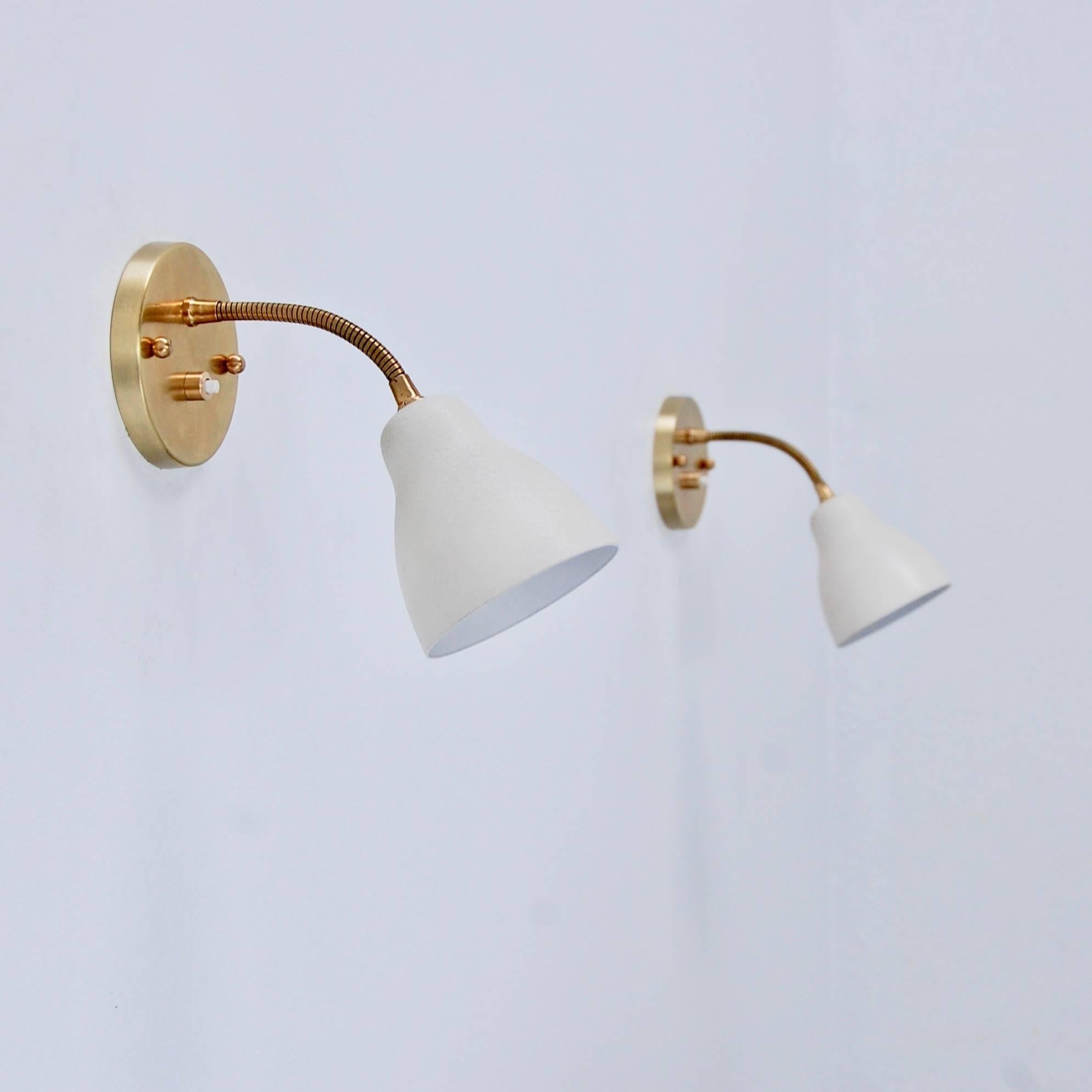 A pair of French 1950s petite gooseneck sconces. Brass and painted off white aluminium finish with a single E12 based socket per glass shade. Back plate has 2 ¾” centre to centre mounting holes. Currently wired for use in the
