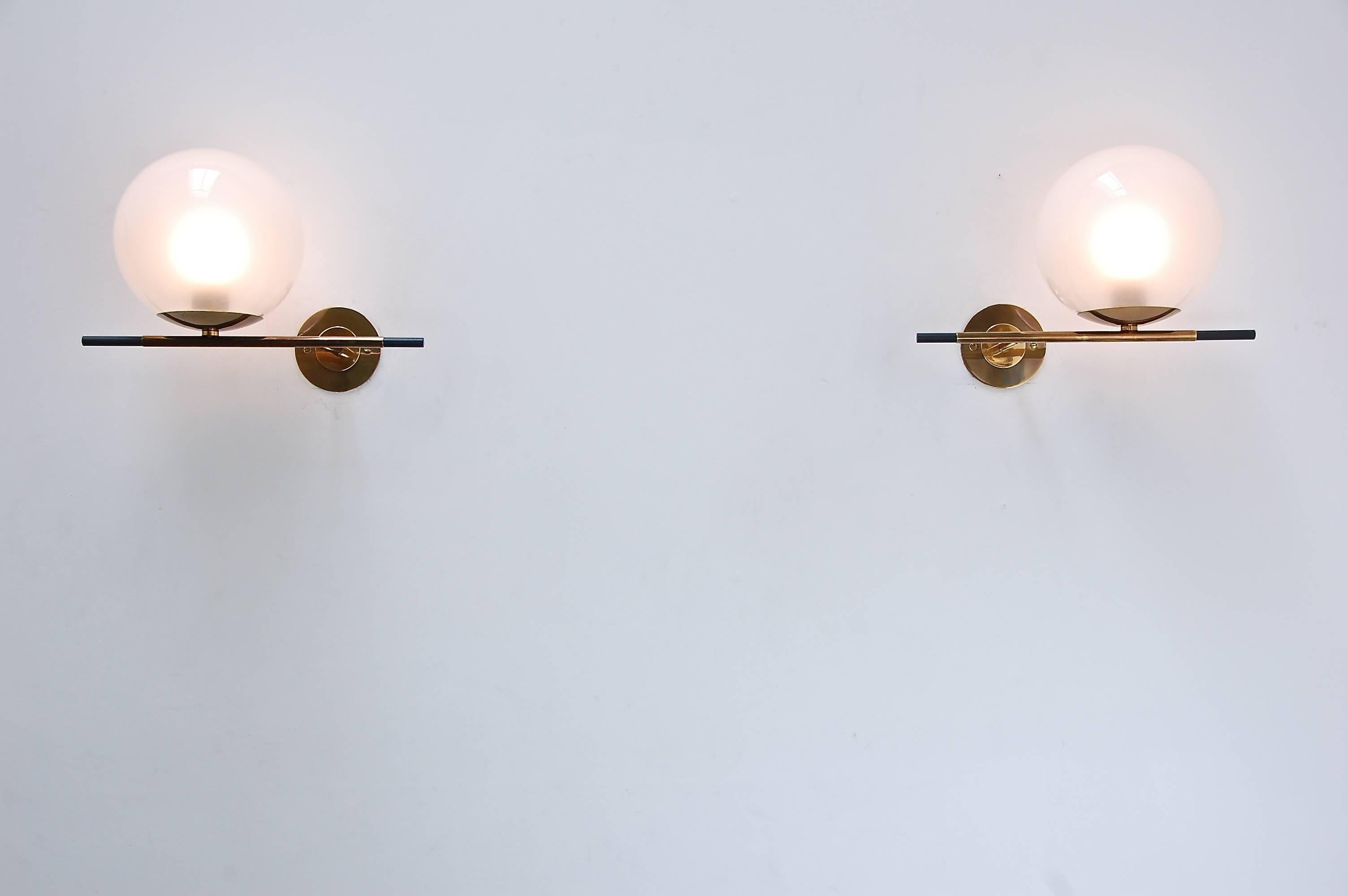 Geometrische und ikonische Globe Sconces. Diese Leuchter spielen mit dem Gleichgewicht von Gewichtswahrnehmung und Stärke und zeigen die Spannung, die durch das Rollen einer Kugel über eine Kante entsteht. Der weiche Schirm aus mundgeblasenem Glas