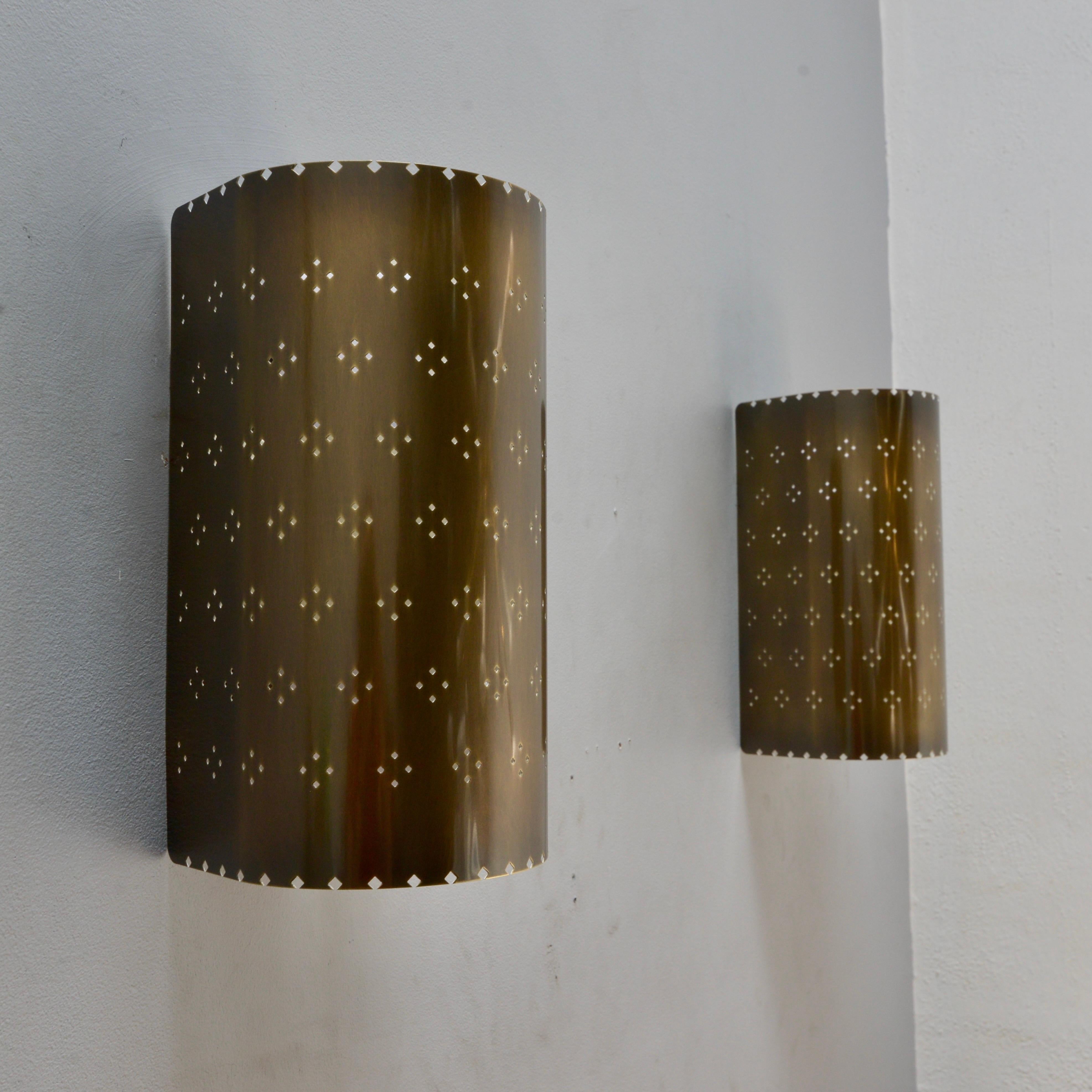 El atractivo aplique LU Louis PB Outdoor es una versión para exteriores del aplique de pared totalmente de latón en acabado de latón patinado con perforaciones estampadas de Lumfardo Luminaires. De fabricación contemporánea en EE.UU. Múltiplos