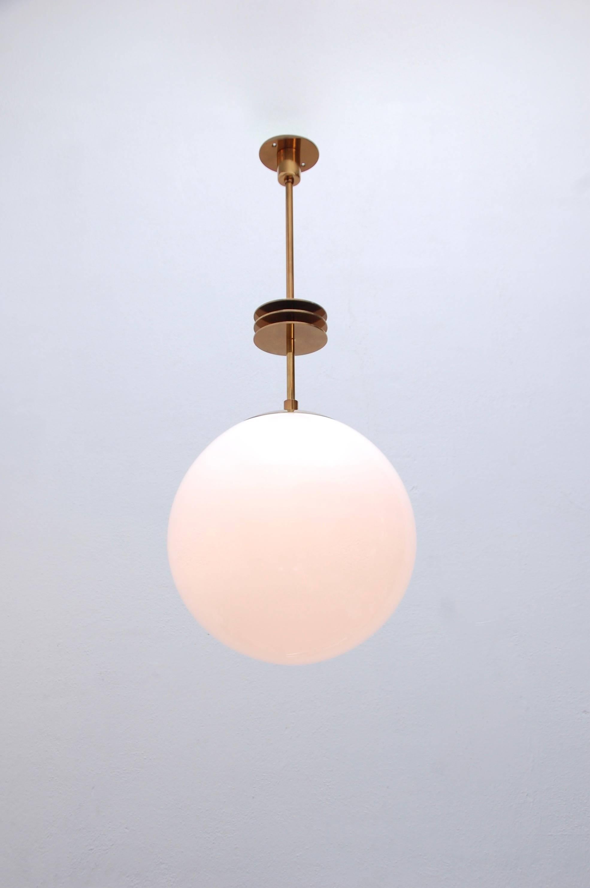 The LU Deco Pendant is a contemporary fixture. This fixture is a lovely globe pendant with Art Deco inspired design features. Choose between two finishes: lightly aged lacquered brass (LALB) or patinated brass (PB) and hand blown glass. Wired with a