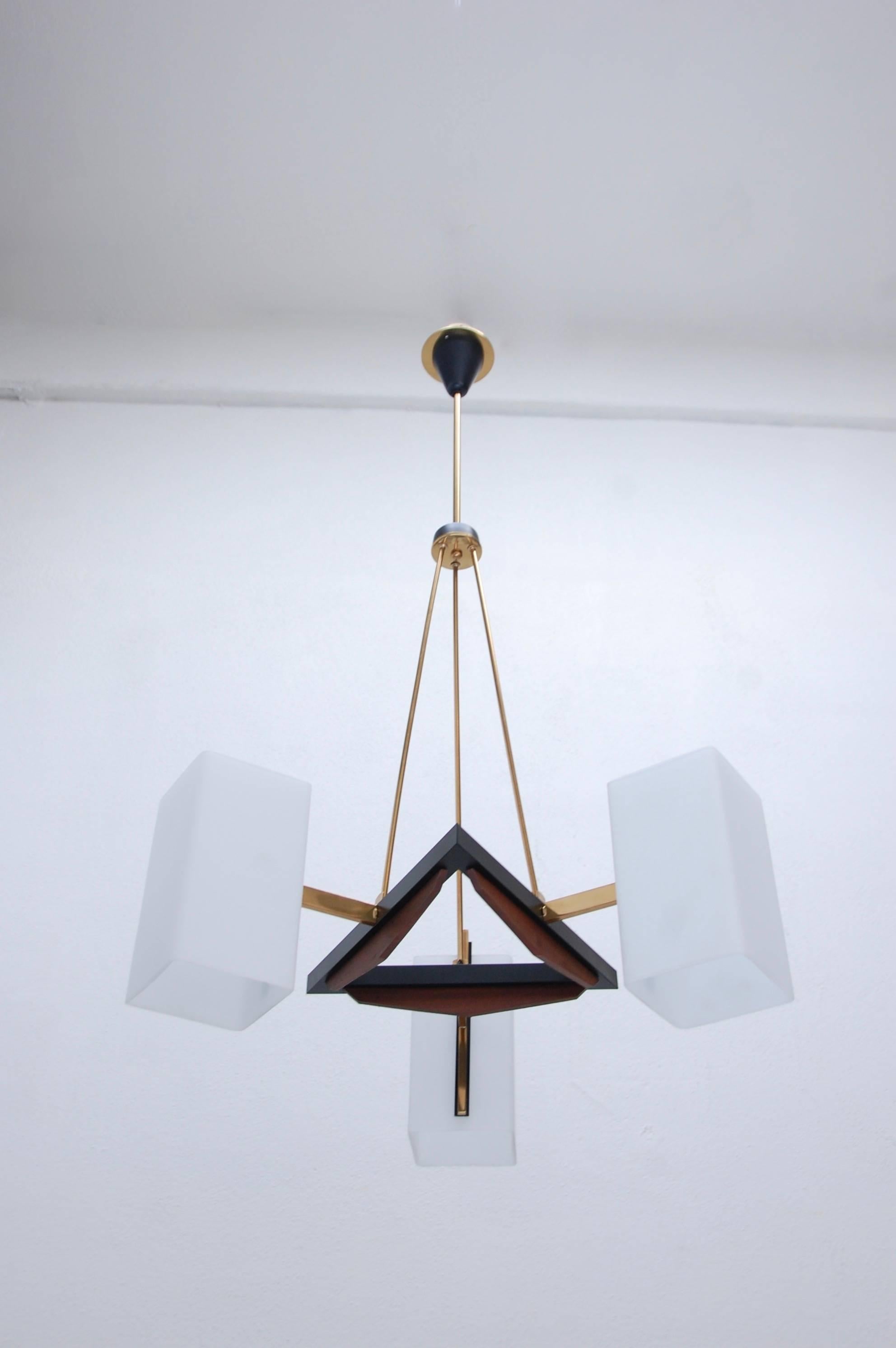 Of the period Italian triangular chandelier in brass, glass and teak wood, with three glass shades from the 1950s. Fully restored, original glass shades, single E12 candelabra based socket per shade, wired for the US. Overall drop adjustable upon