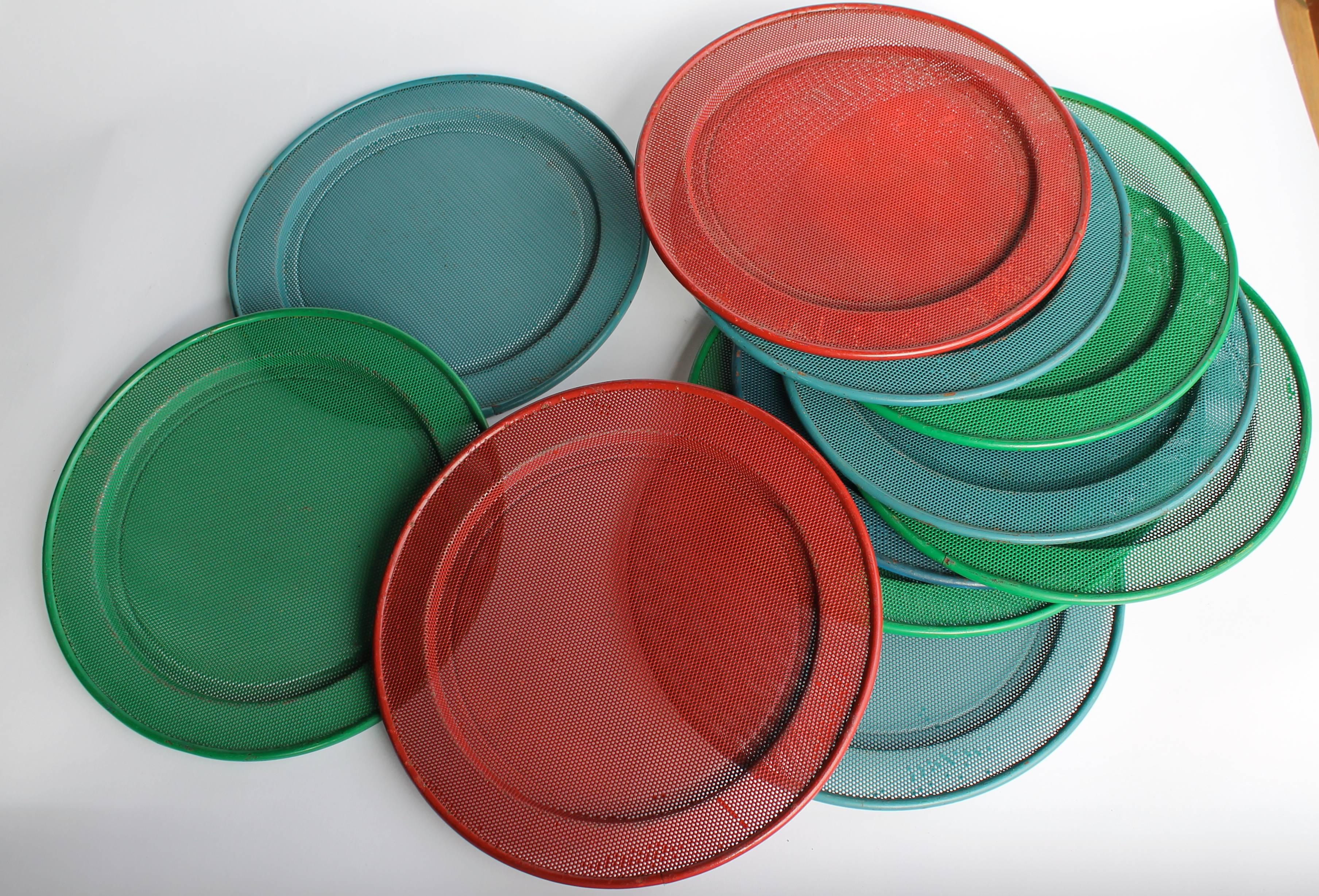 Vintage set of 11 perforated enameled metal dishes or trays. 
In the style of Mathieu Matégot. 
Two red,
five blue,
four green.
Beautiful original vintage condition.