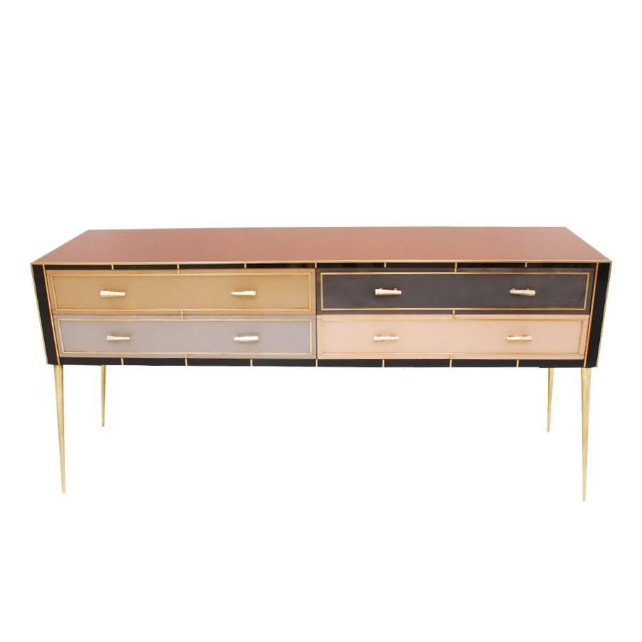 Four-drawer sideboard with wooden structure covered in colored glass and composed by profiles, handles and brass feet.
