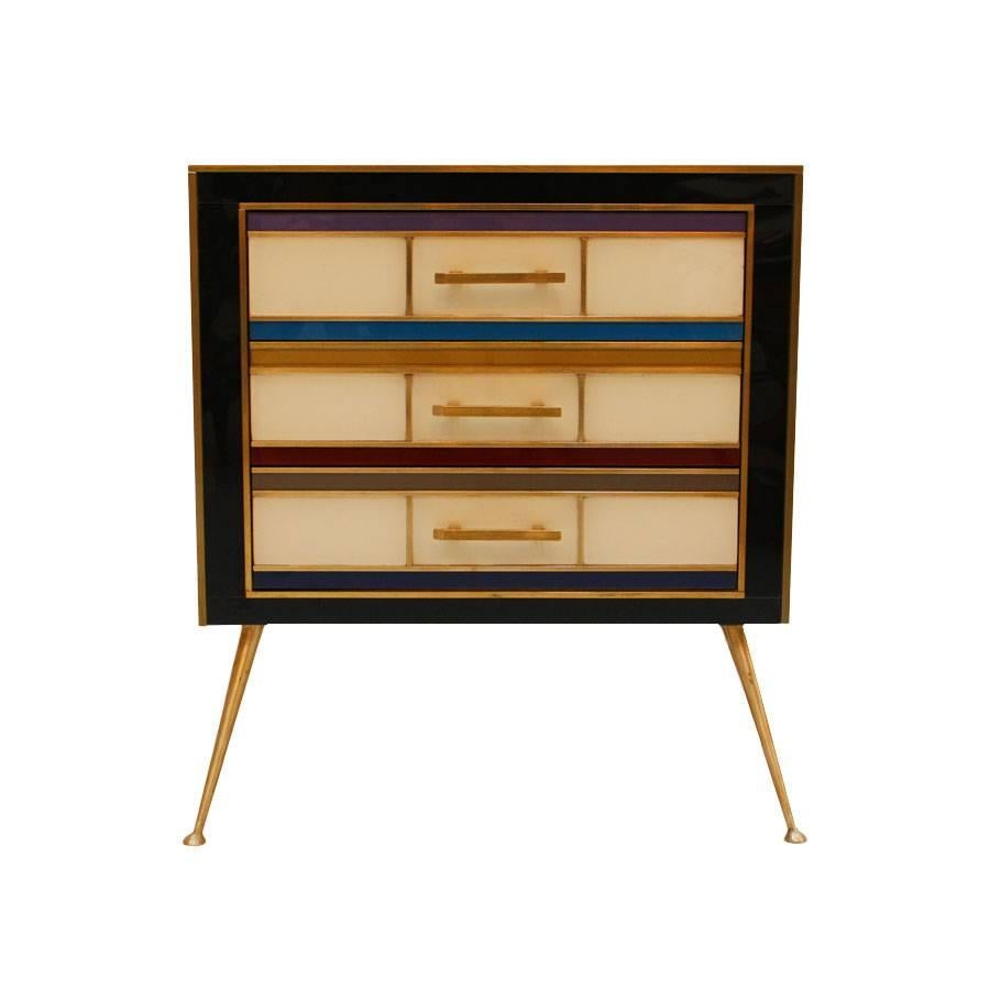 Pair of night stands with three drawers with structure in solid wood, covered in colored glass and brass details.