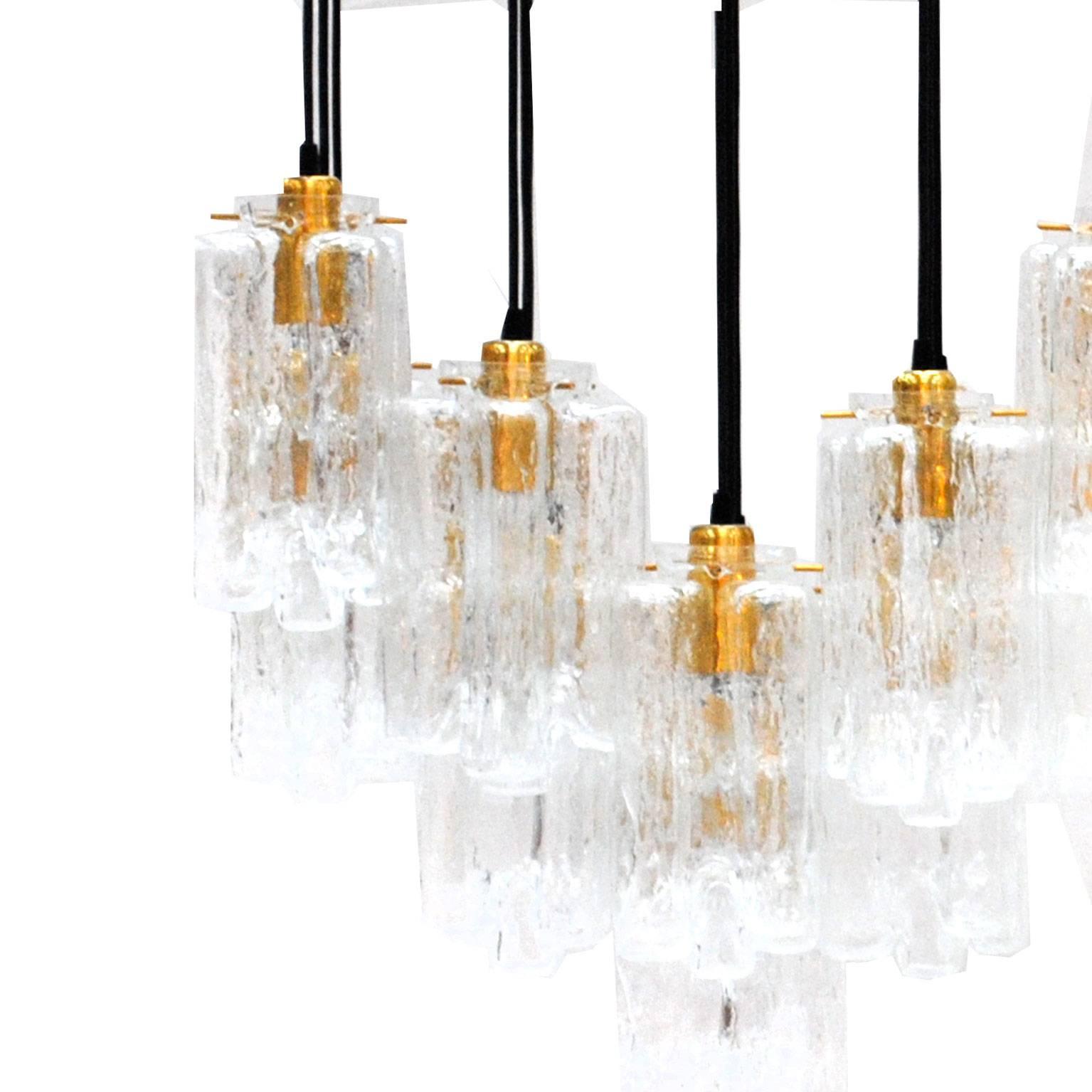 Suspension lamp composed by thirty light points finished on sculptural carved crystal with details in brass.