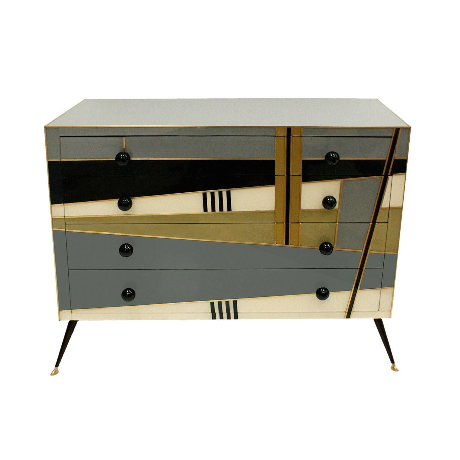 Commode composed by four drawers, made in solid wood covered in Murano glass in geometrical pattern with legs and hangers in brass.