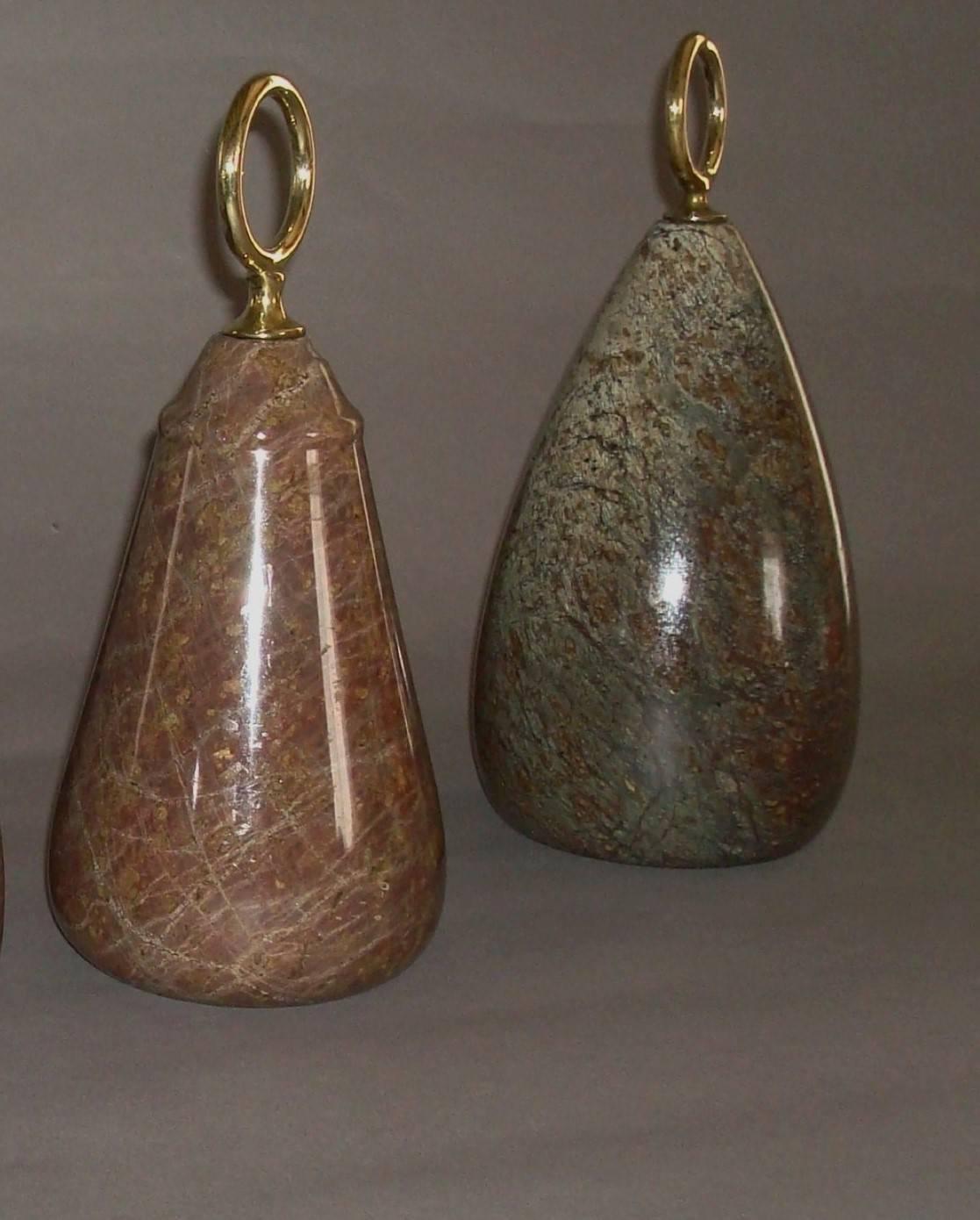 Two unusual 19th century Serpentine marble door stops; mounted with brass circular carrying handles, above ovoid shaped 'Serpentine' marble bodies.

Largest measures 9.75 ins high, 4.5 ins diameter;
Smallest measures 9.25 ins high, 4.25 ins