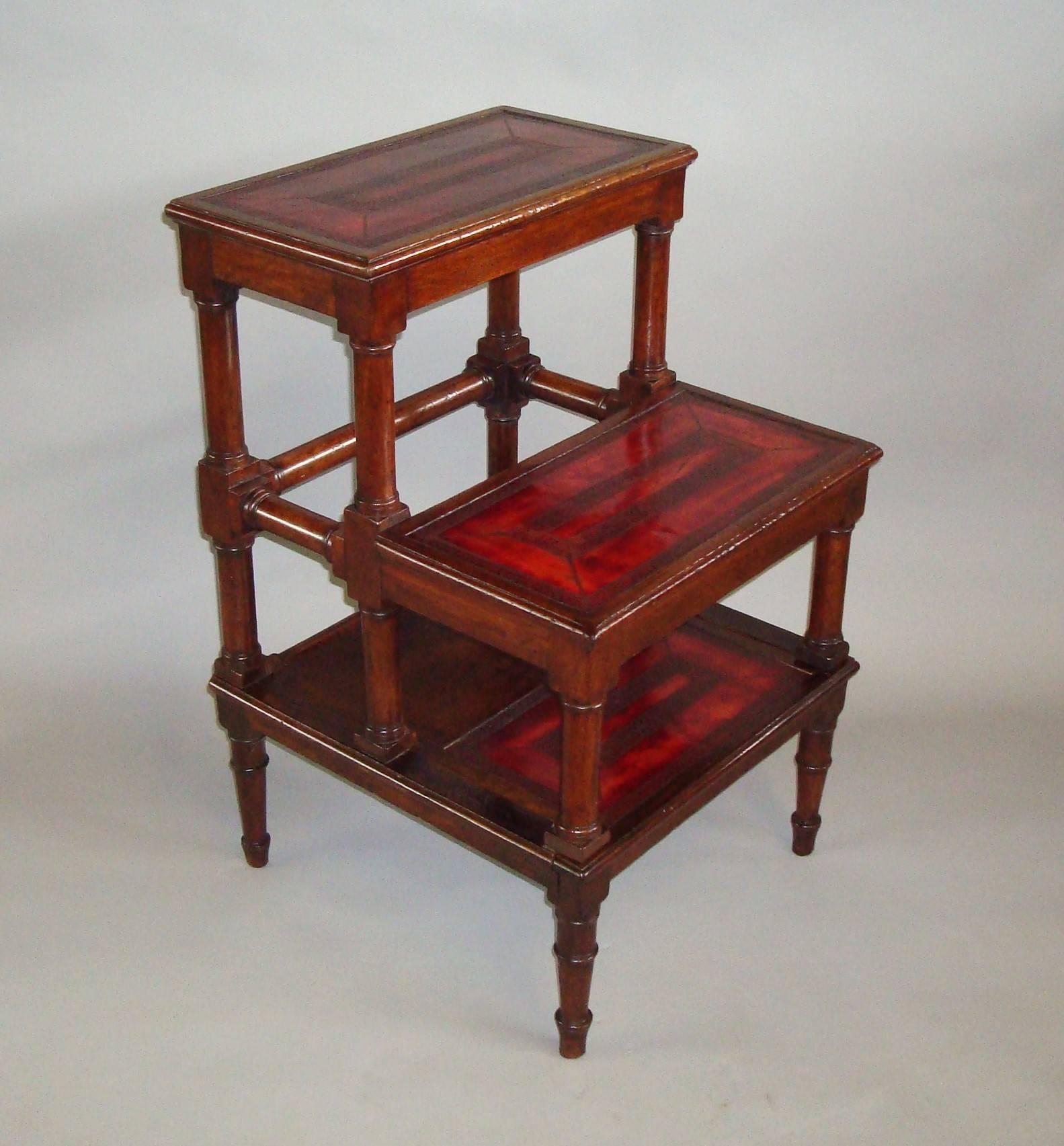 A good George III mahogany set of library steps of unusual form, the three treads with moulded edges inset with good quality burgundy leather incorporating faded areas and heavily tooled with foliate designs and a good patination, raised on turned