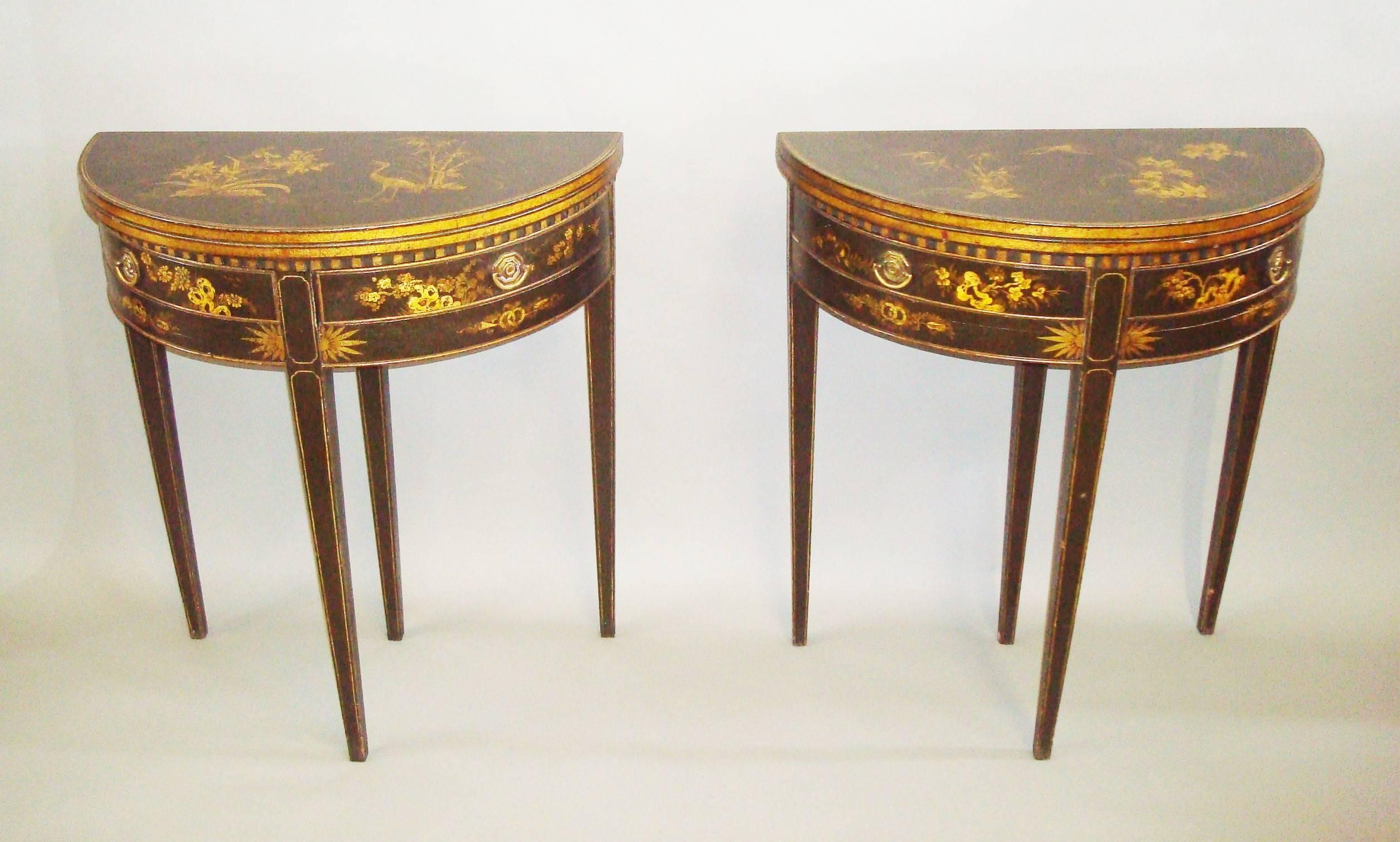 Late 19th century pair of chinoiserie lacquered demilune card tables; of small proportions with gilt decoration on a dark green background. The fold over tops decorated with Eastern birds, trees and foliage in a landscape. The interiors with a
