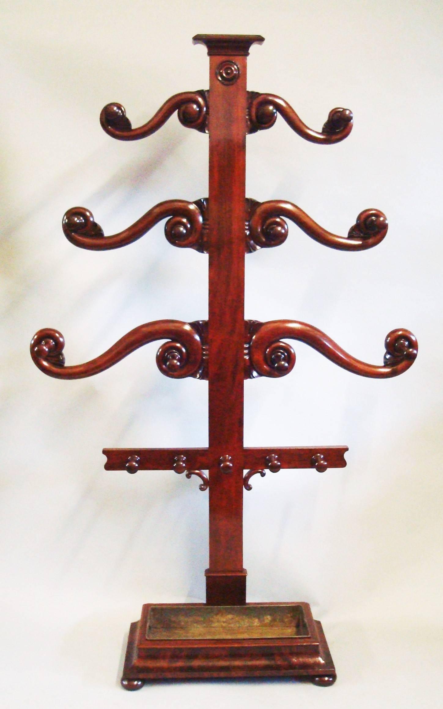 An impressive George IV mahogany 'tree' hall stand of large proportions; for hats, coats, sticks and umbrellas.

The figured mahogany central pillar headed with a moulded capital and carved rosette below, supporting six graduating 'S' scroll arms
