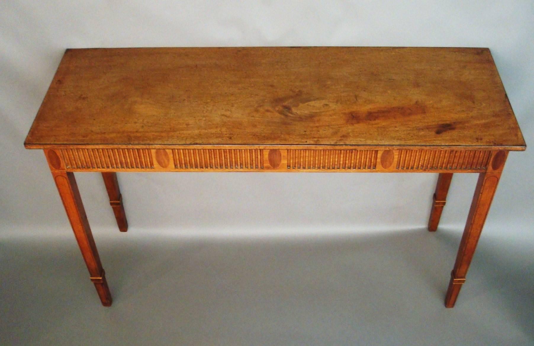 A good George III mahogany neoclassical console table or side table of elegant proportions; the figured rectangular top with an ebony strung edge, raised on a fluted frieze separated by oval inlaid panels, repeated on the sides. Standing on square