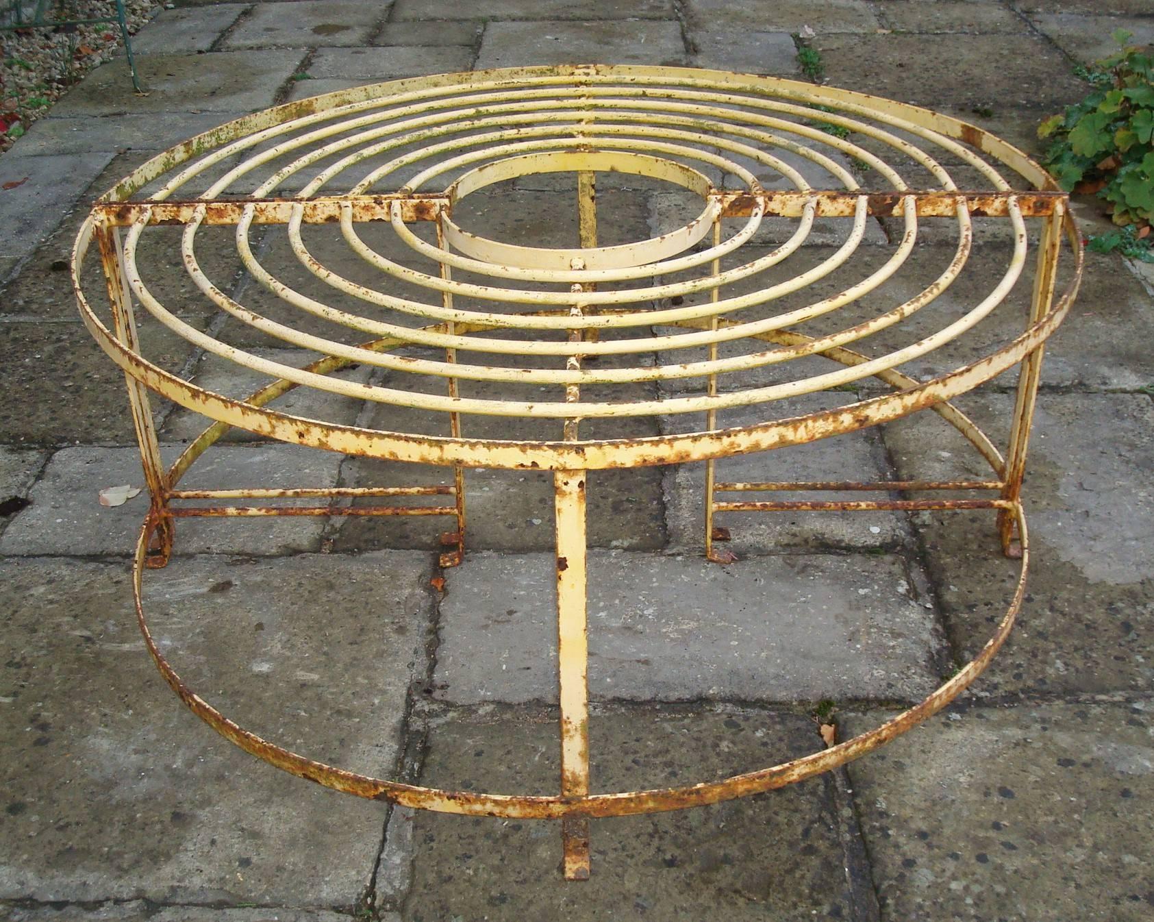 Early 20th century wrought iron garden tree seat, consisting of a pair of demilune seats with kickout feet. Can be used separate or together as a circular tree seat. Retaining much of the original ochre paint,
English, circa 1920.
Good