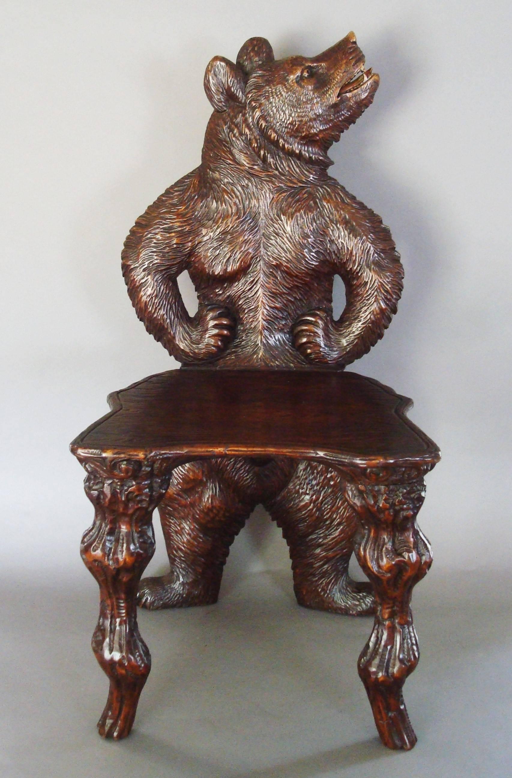 A superb 19th century Black Forest carved bear hall chair; the standing bear with attitude and his head raised with his mouth open showing his polychrome teeth and tongue, his arms and front paws resting on his hips in a whimsical fashion. The