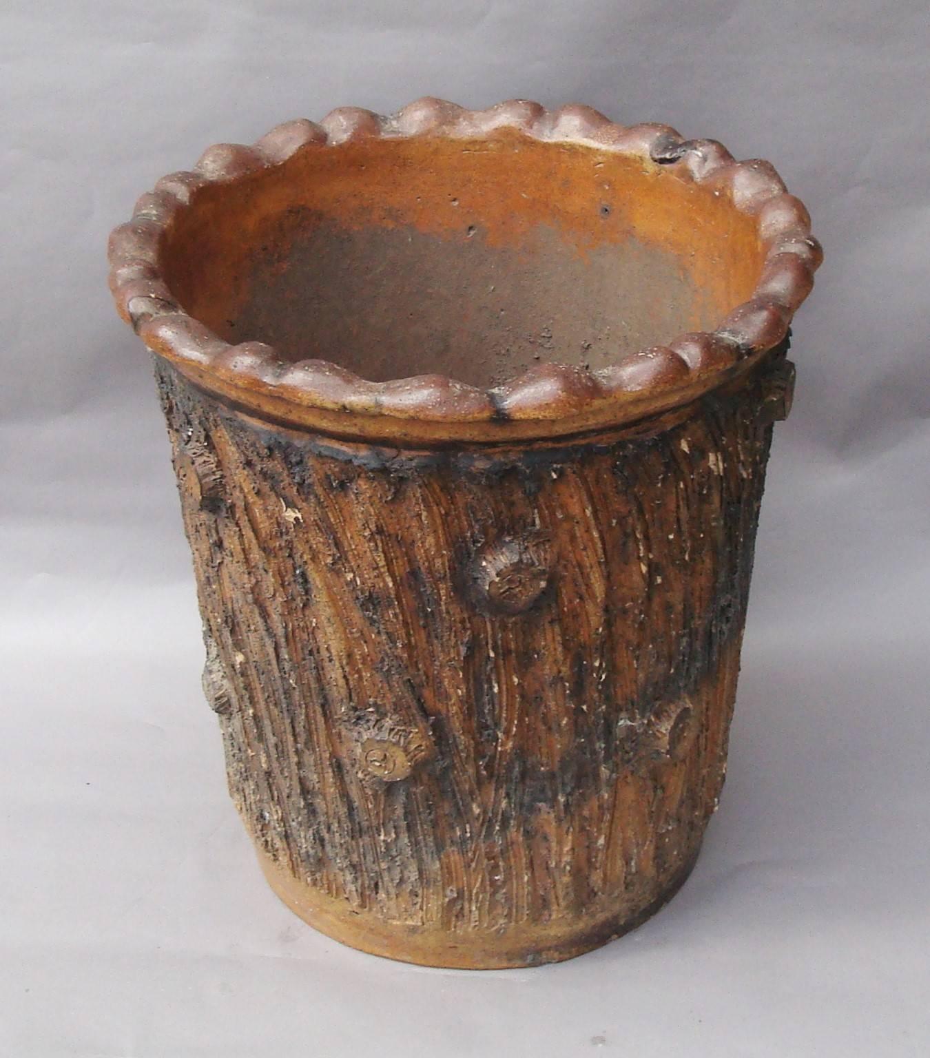 A large 19th century bark pattern jardinière or log bin in glazed pottery; the top with a wavy moulded edge above the slightly tapering main body with realistic bark and stump effect,
English, circa 1870.
Excellent condition, very minor
