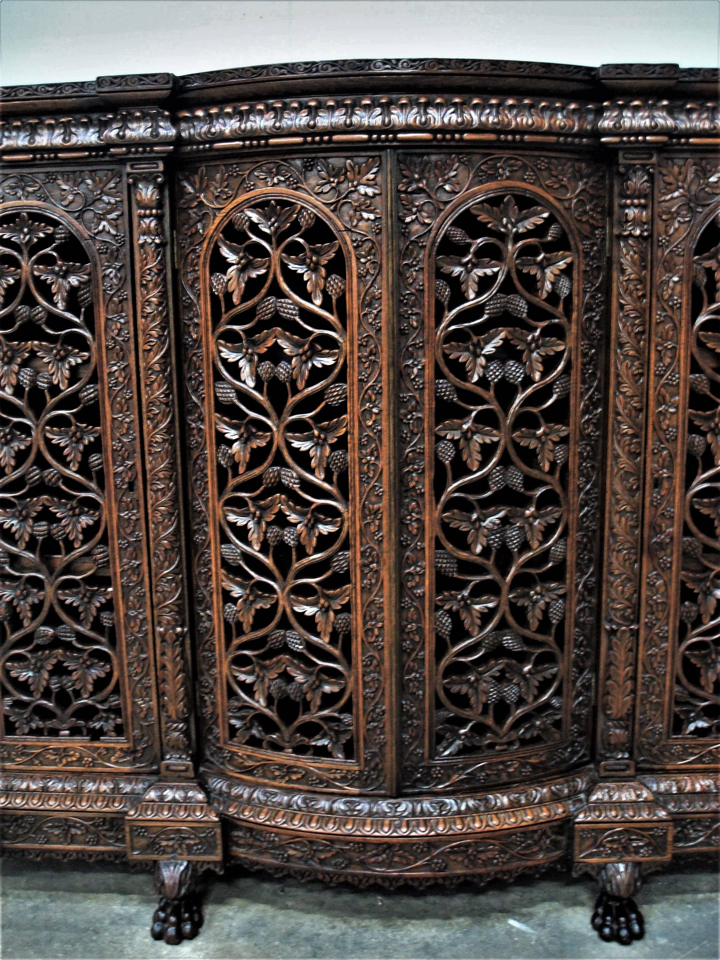 Impressive 19th century Indian carved padouk side cabinet; profusely carved with Fine detailing throughout. The figured top, with shaped outline to the front, above a shaped frieze with acanthus leaf carving. The pair of central doors being bow