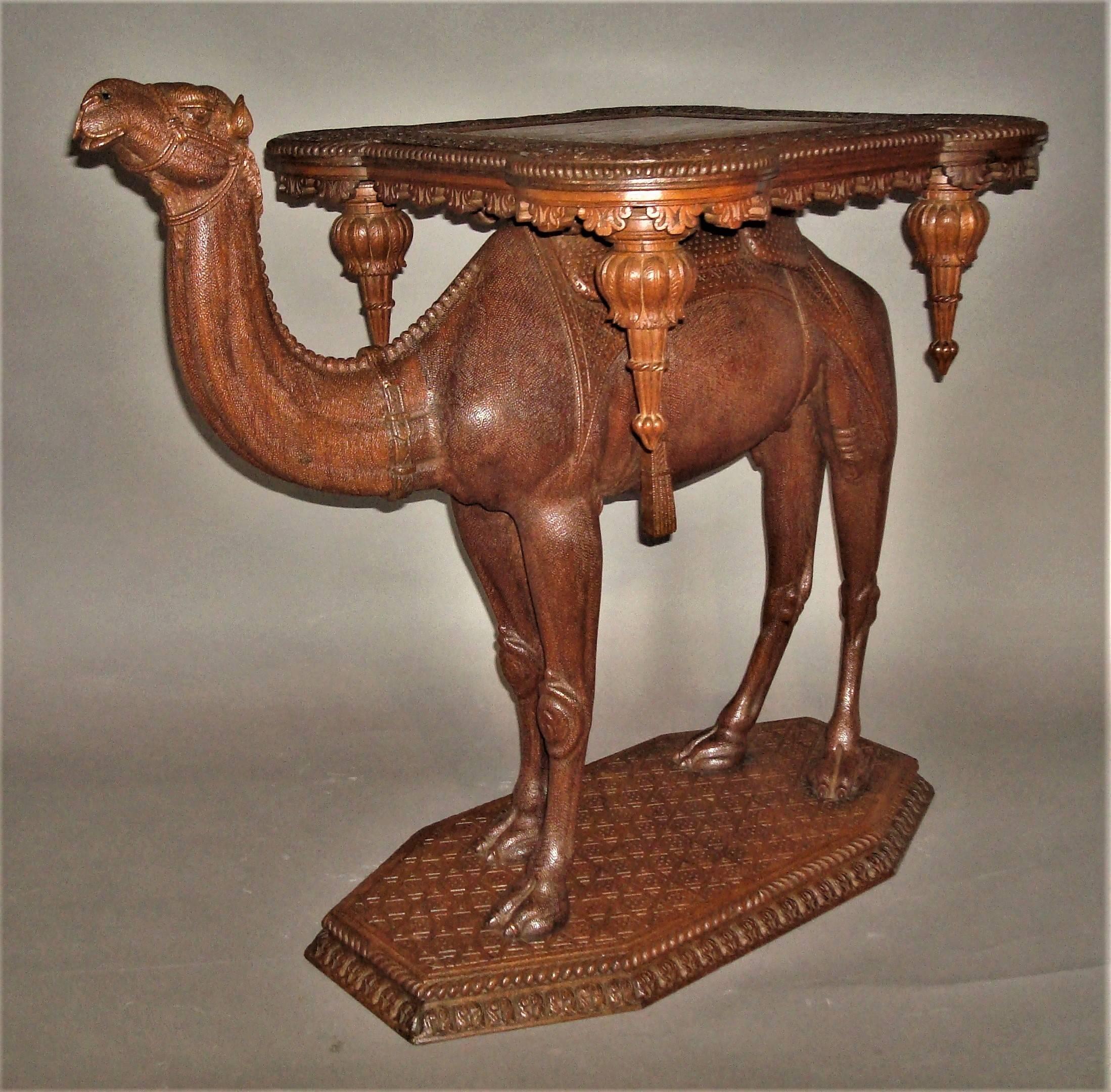 Exceptional 19th century Anglo-Indian carved camel table, a good quality example with fine carving. The unusual shaped square top, with protruding circular corners, having a central square panel and a border profusely carved in relief, with trailing