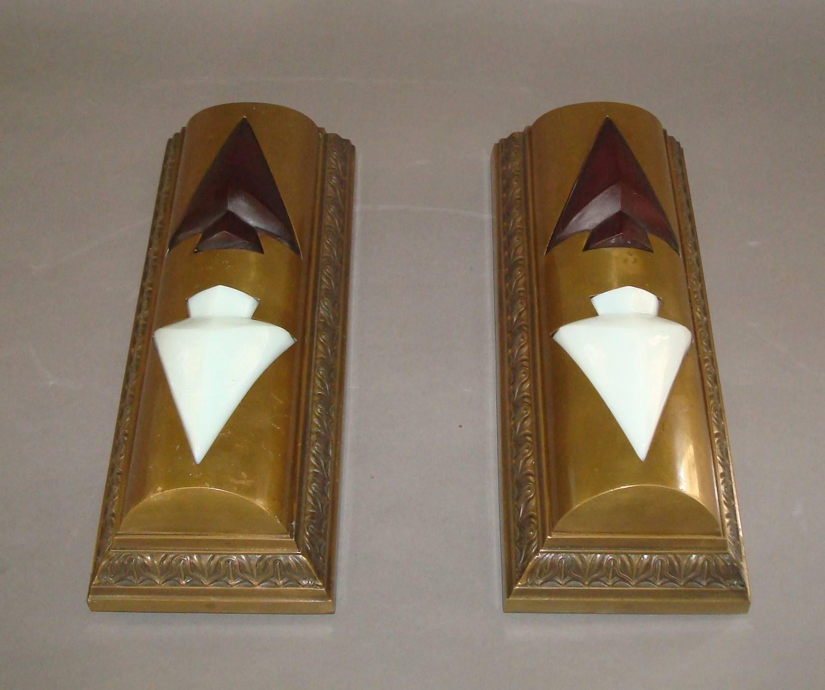 An unusual pair of bronze elevator indicator lights; of rectangular form with a cast anthemion moulding, the domed front housing the raised arrows in red and white glass. 

With original iron back plate and fittings which hold two bulbs.