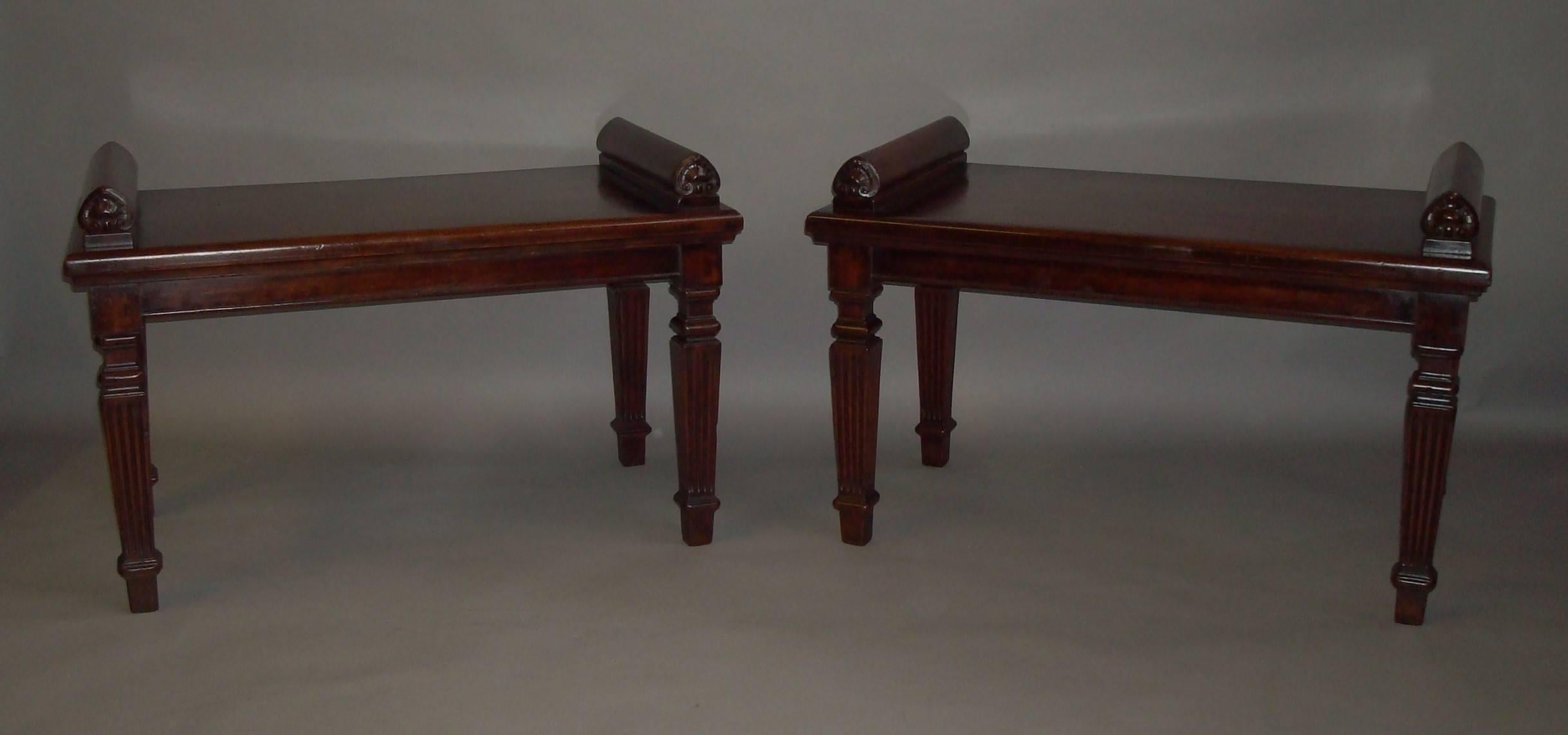 A good late Regency pair of mahogany hall seats, the well figured rectangular tops with a moulded edge and raised, shaped, bolster supports to either side, with carved anthemions to the front; on a simple shallow frieze raised on neo-classical