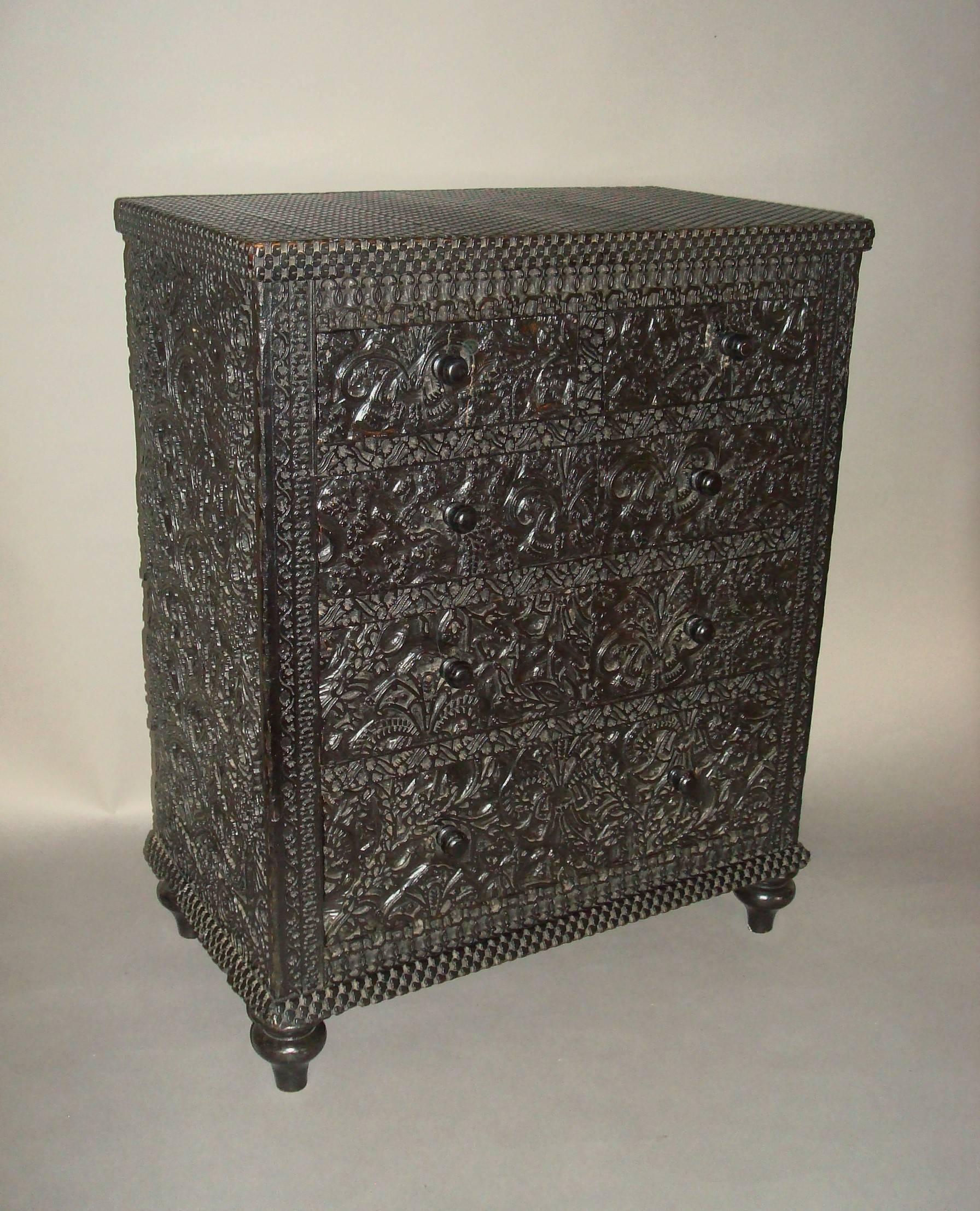 A rare 19th century small ebonized chest of drawers; the whole of the chest unusually faced with printing blocks, the top of geometrical design above two short and three long drawers with intricately carved paisley designs; the sides with similar