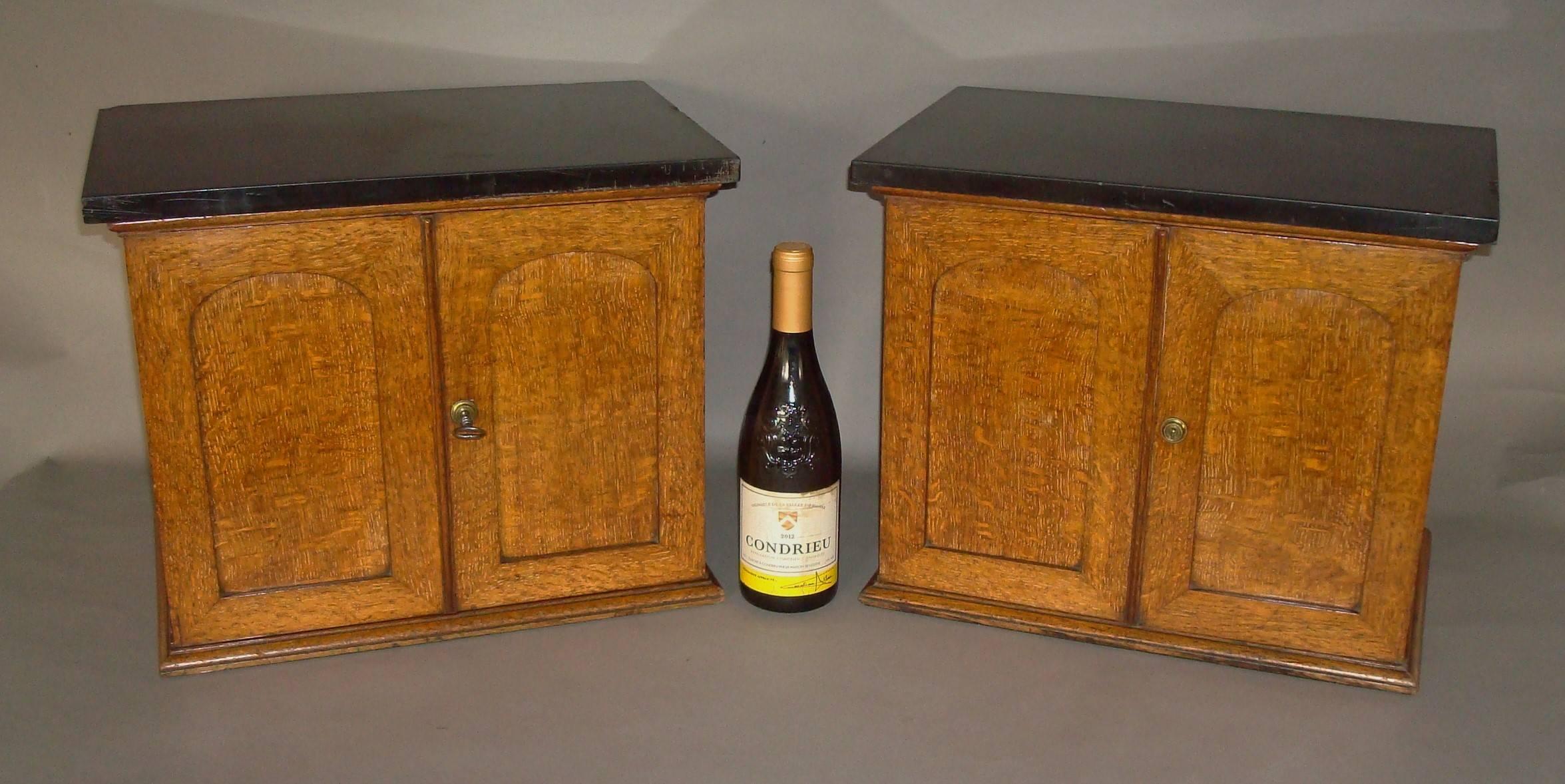Good quality 19th century pair of golden oak table cabinets; the rectangular 'Belgian Black' marble tops, above a pair of arched paneled doors fitted with Bramah locks (stamped 'J Bramah, 124 Piccaddilly' with a crown). The mahogany interiors one