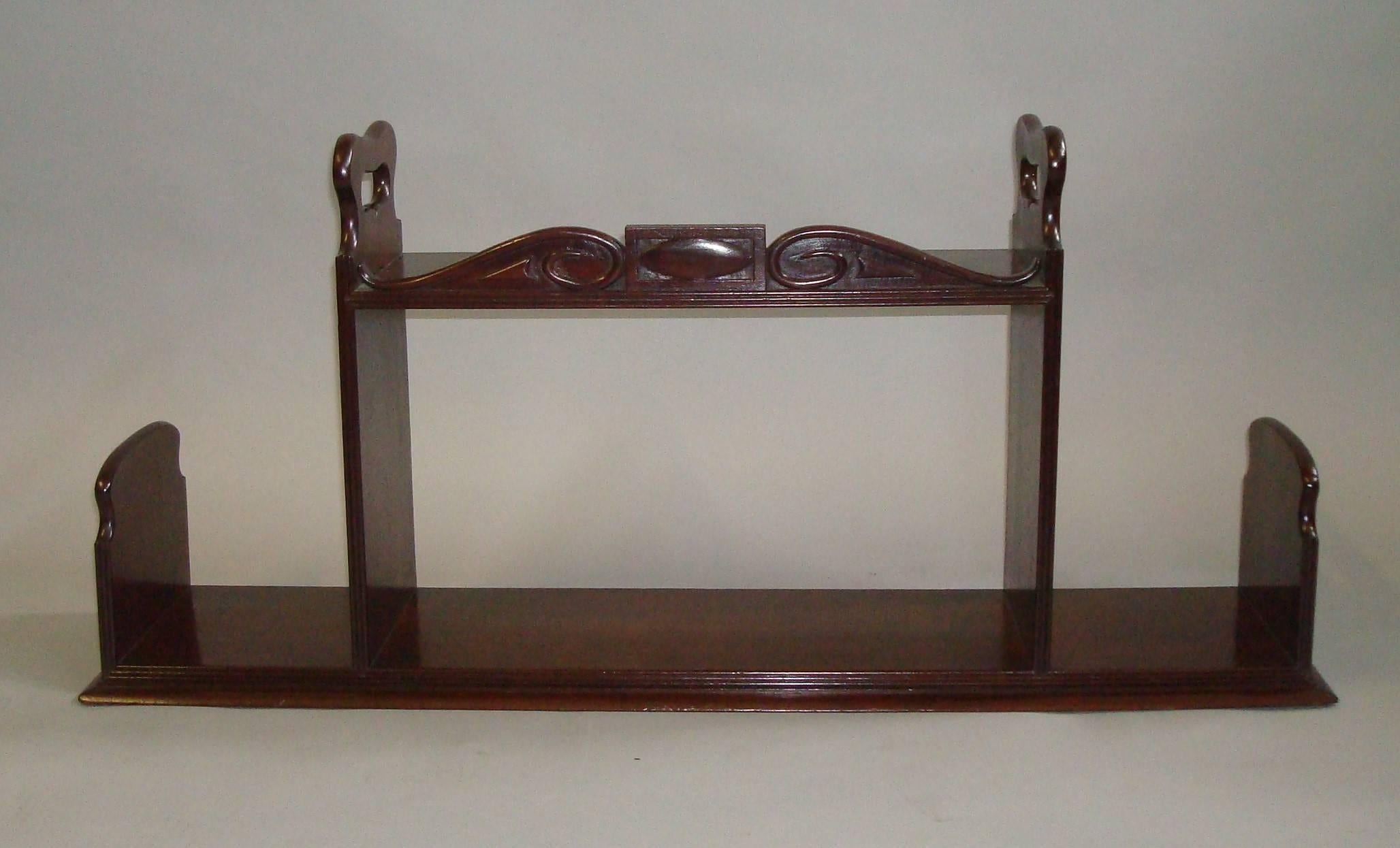 Regency mahogany book carrier / bookstand of unusual form and large proportions; the centre section with reeded edges and a carved scroll cresting and raised shaped carrying handles to either side, the reeded rectangular base with open sections to