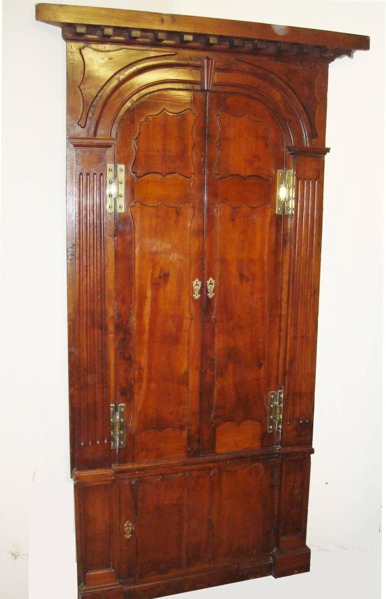 An impressive and rare, Georgian Irish yewwood standing corner cupboard of architectural form; the overhanging cornice with shaped dentil brackets above an arched frame with shaped applied corner panels. The pair of arched doors with applied panels