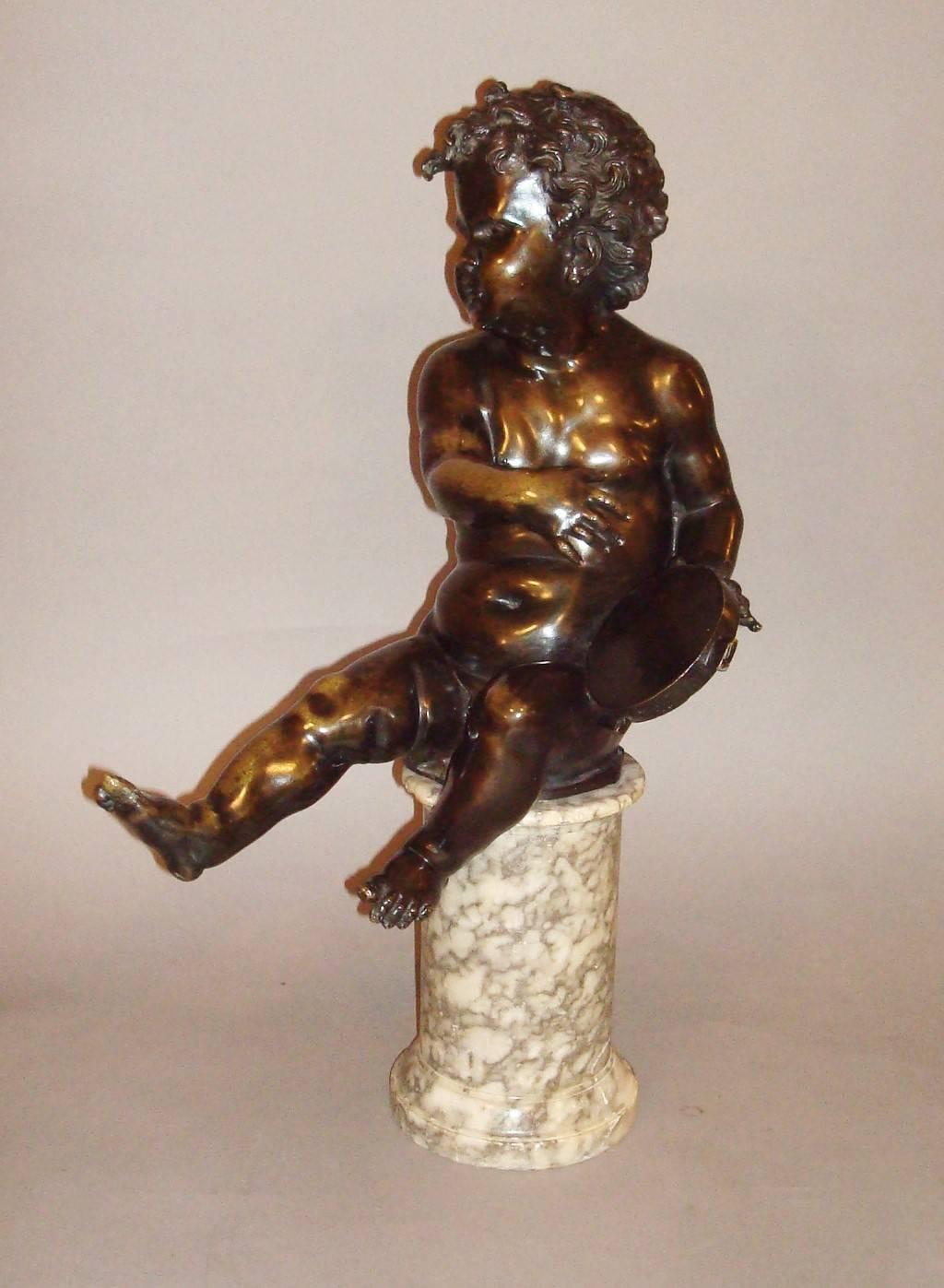 19th century bronze sculpture of a putti / cherub of large proportions, the putti is in a seated position playing a tambourine, with one leg stretched out; sat on an alabaster marble circular pedestal with a stepped moulded plinth base. Good rich