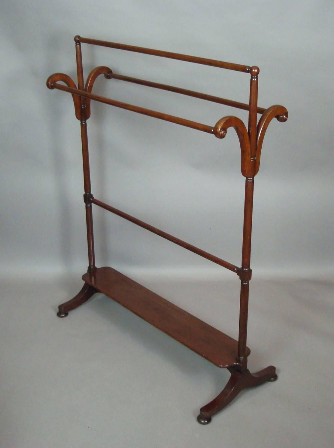 A late Regency mahogany clothes/towel rail, of large proportions. The turned top rail with ball finials above scrolled brackets with reeded roundels supporting two further rails on turned uprights. Having the unusual feature of useful bottom shelf,