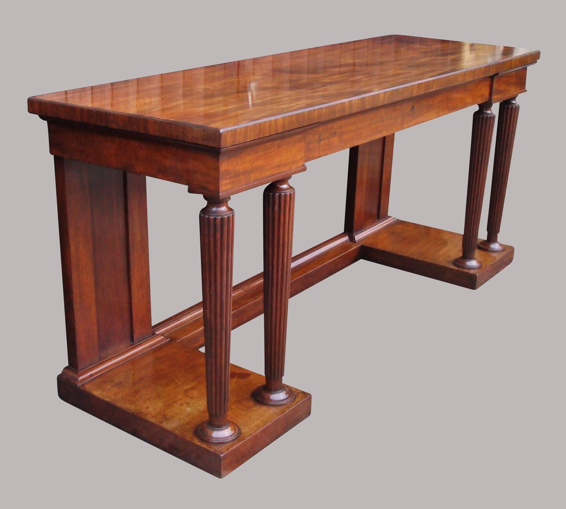 An imposing Regency mahogany neoclassical side table serving table, in the manner of Gillows; the well figured rectangular top with a slender moulding and cross banded edge, above the inverted breakfront frieze incorporating a long central drawer