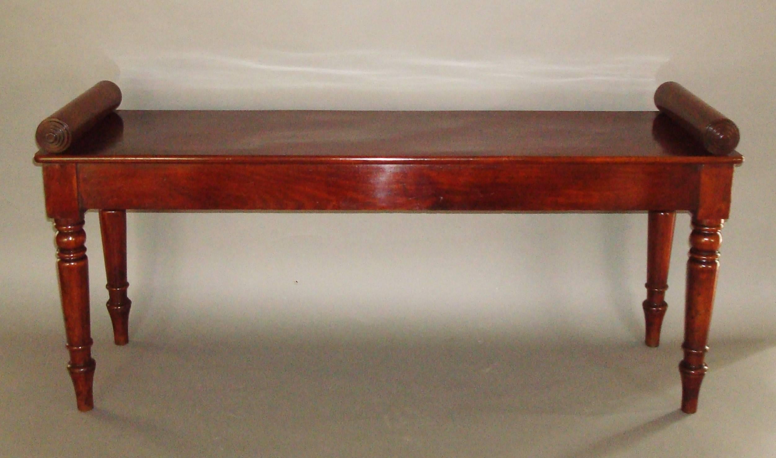Good quality, late Regency mahogany hall bench or window seat; the well figured rectangular seat with raised scrolled ends terminating in turned reeded paterae; above a simple frieze raised on turned tapering legs finished all the way round so can