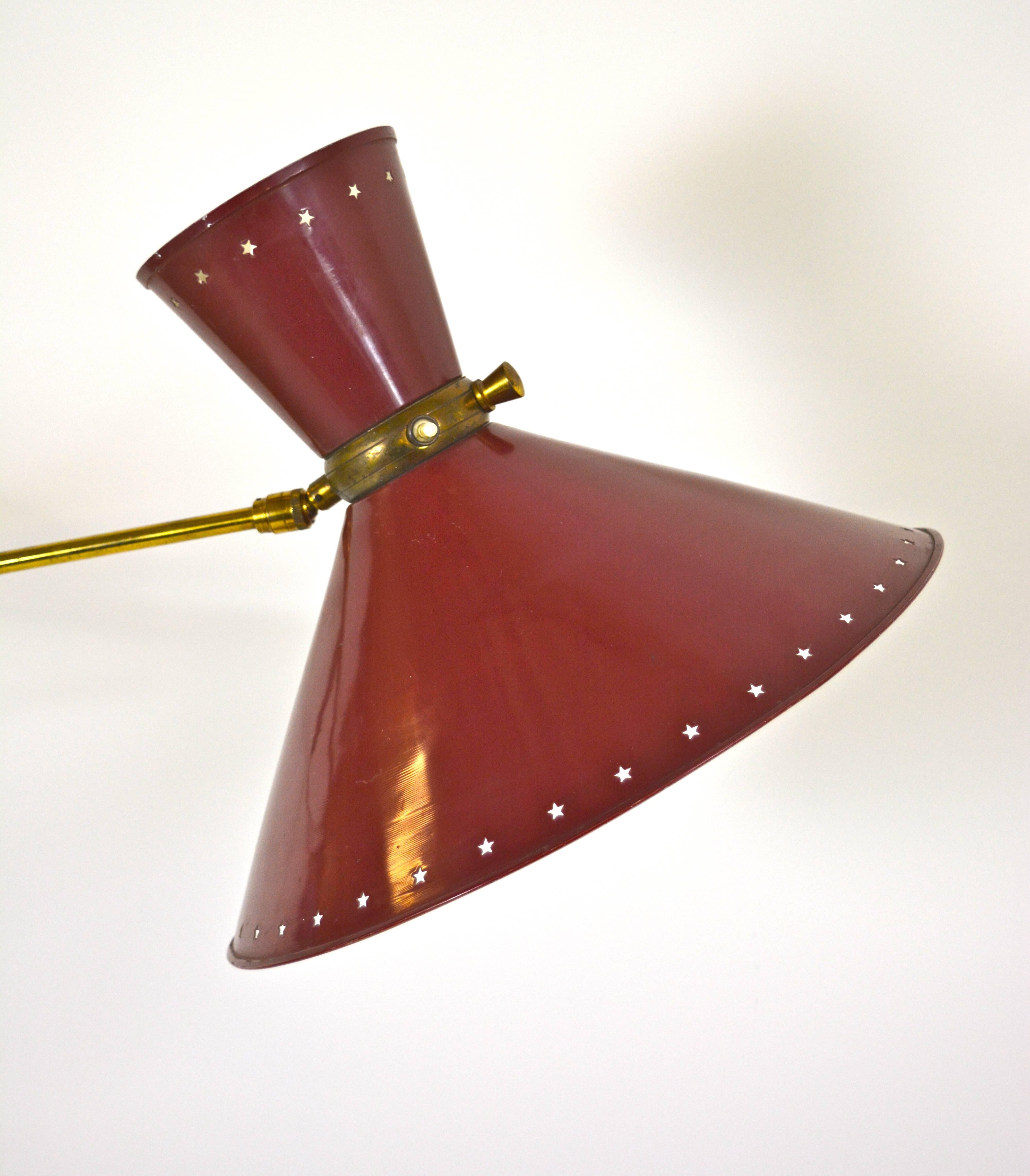 Brass fixture with articulating arm and original enameled red metal shade with star-shaped perforation. Designed by Rene Mathieu for Lunel, France, circa 1950. Light in each cone controlled independently.

 