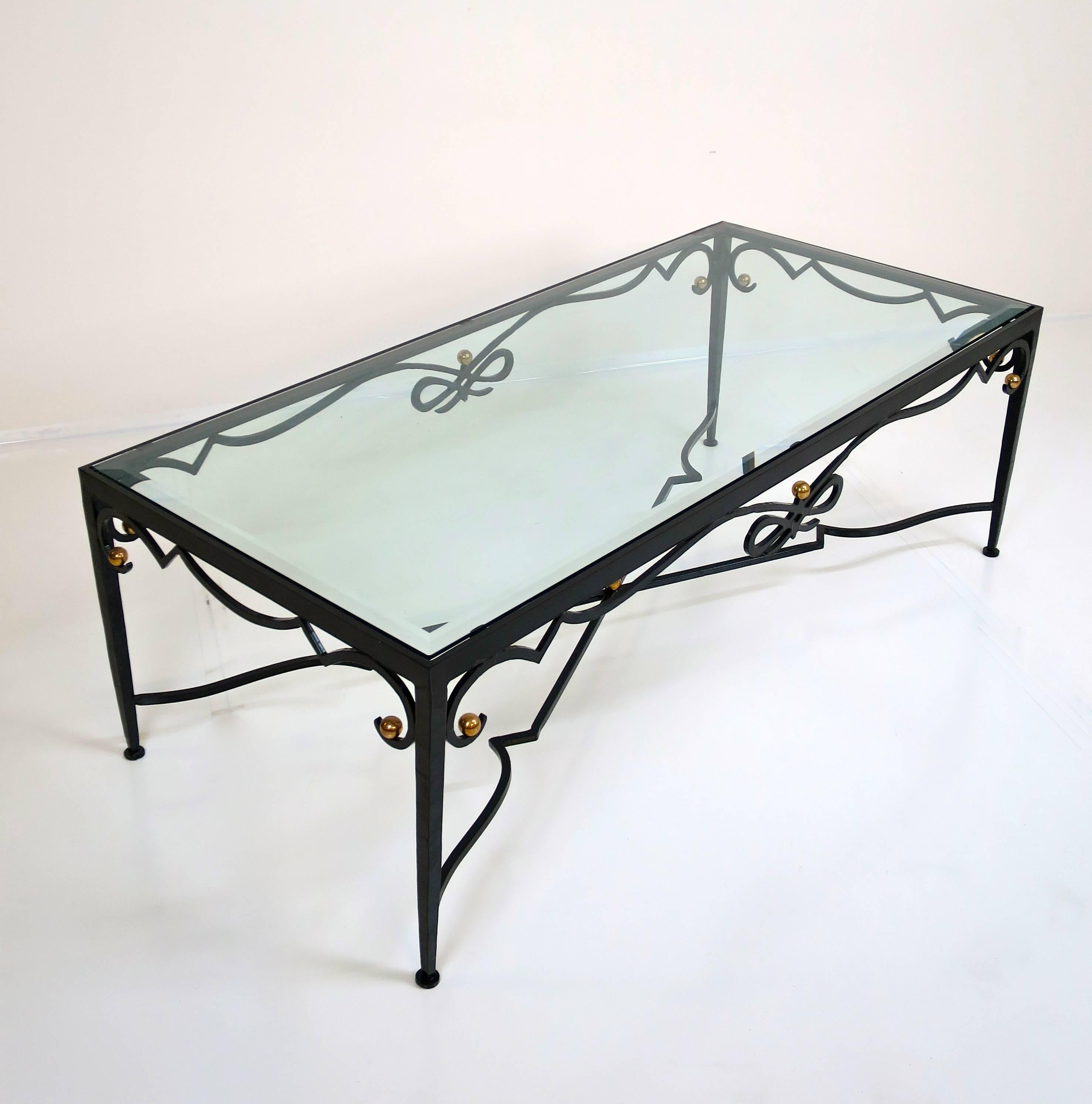 An exceptional French Cocktail table made of forged iron with solid brass details and a beveled glass top, circa 1960's.