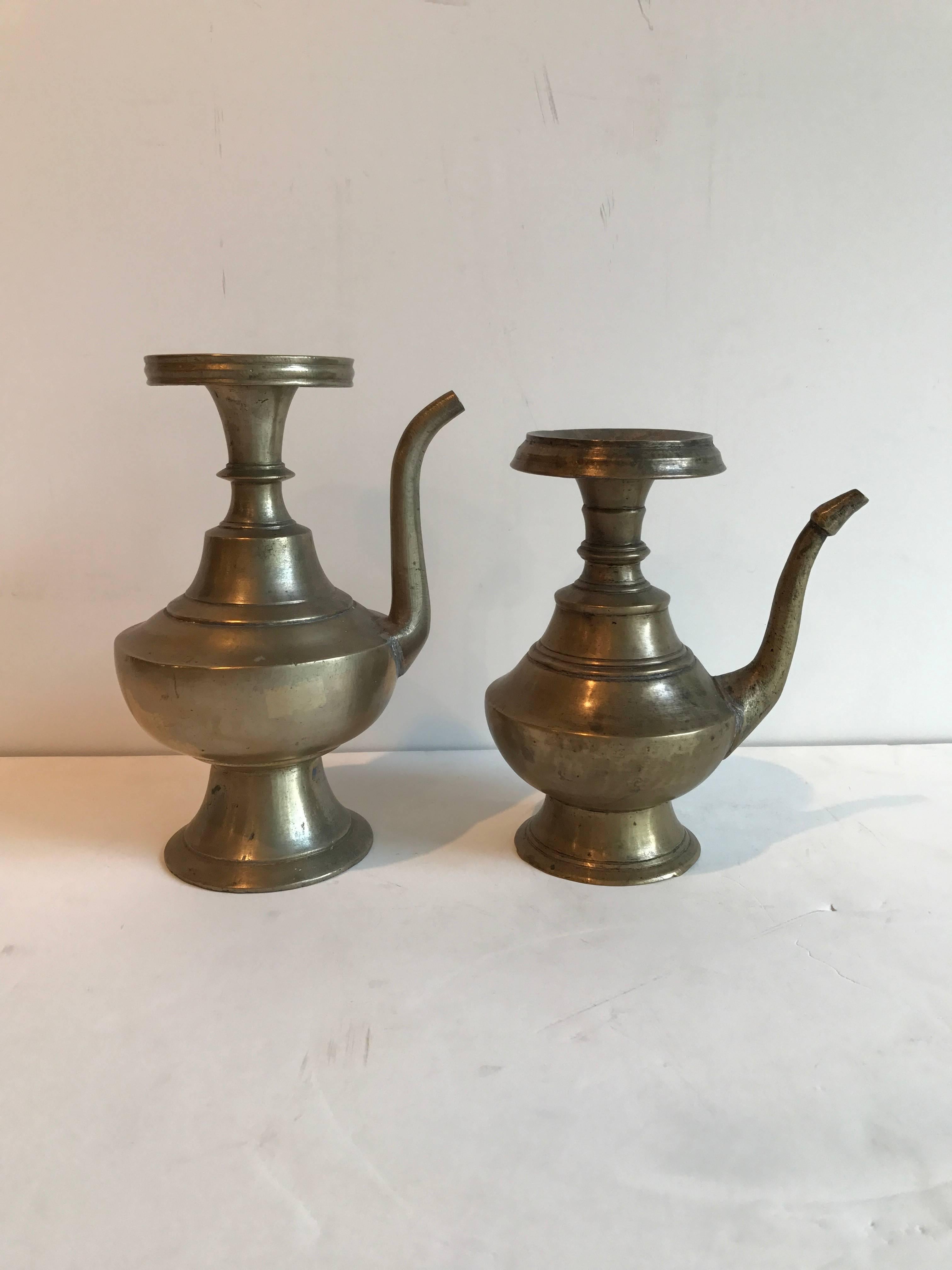 Two classically shaped bronze holy water ewers from the late 19th century. These were used in religious ceremonies in Nepal. 
Dimensions: 
Larger piece: Height:8 diameter:5 .
Smaller piece: Height:7 diameter:3.
HE101.