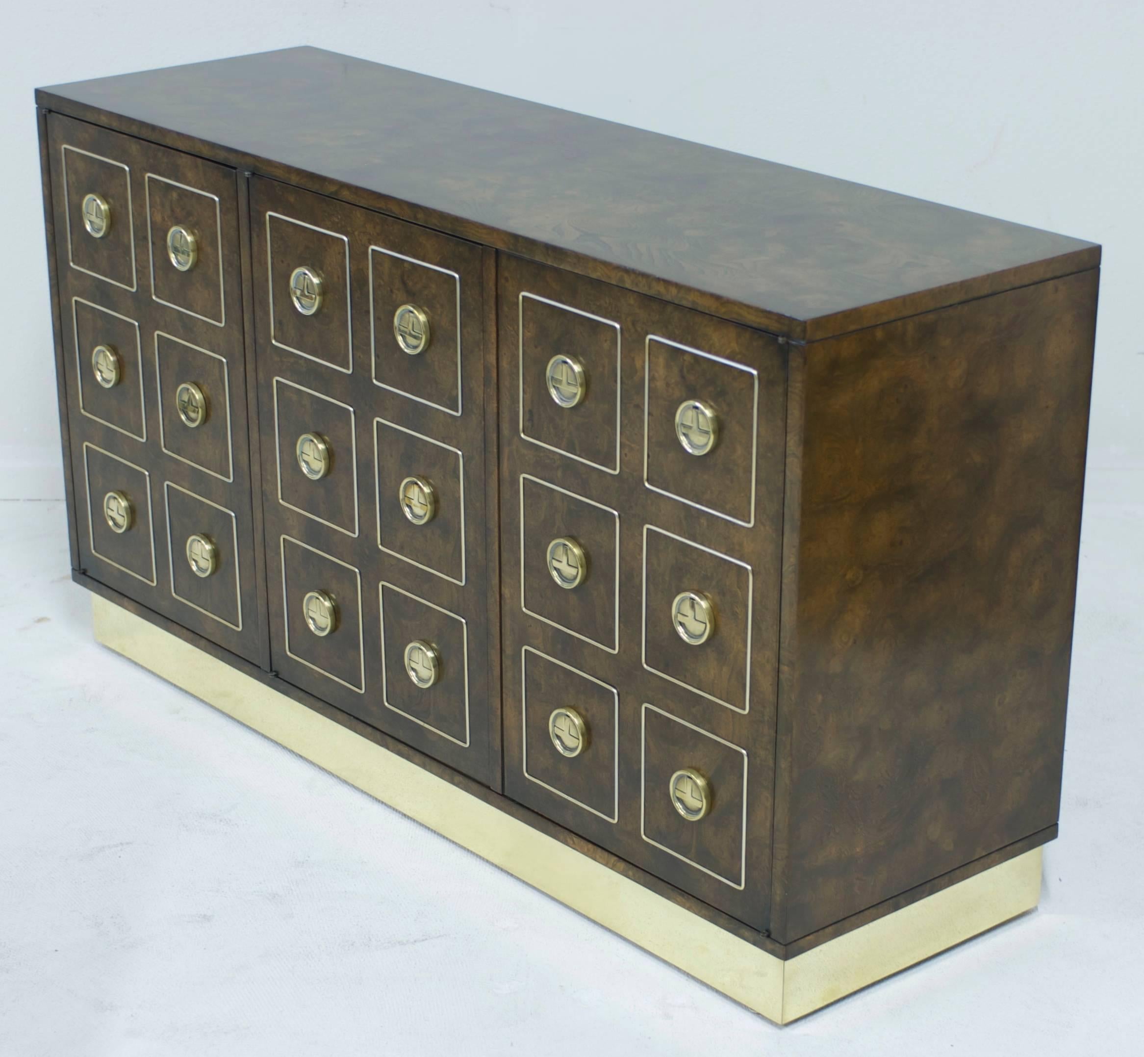 This credenza is in excellent restored condition. There are three doors to the cabinet that hinge open to reveal an adjustable shelf. The Fine amboyna burl wood on this piece has beautiful figuring and a nice golden brown tones.
The brass base and