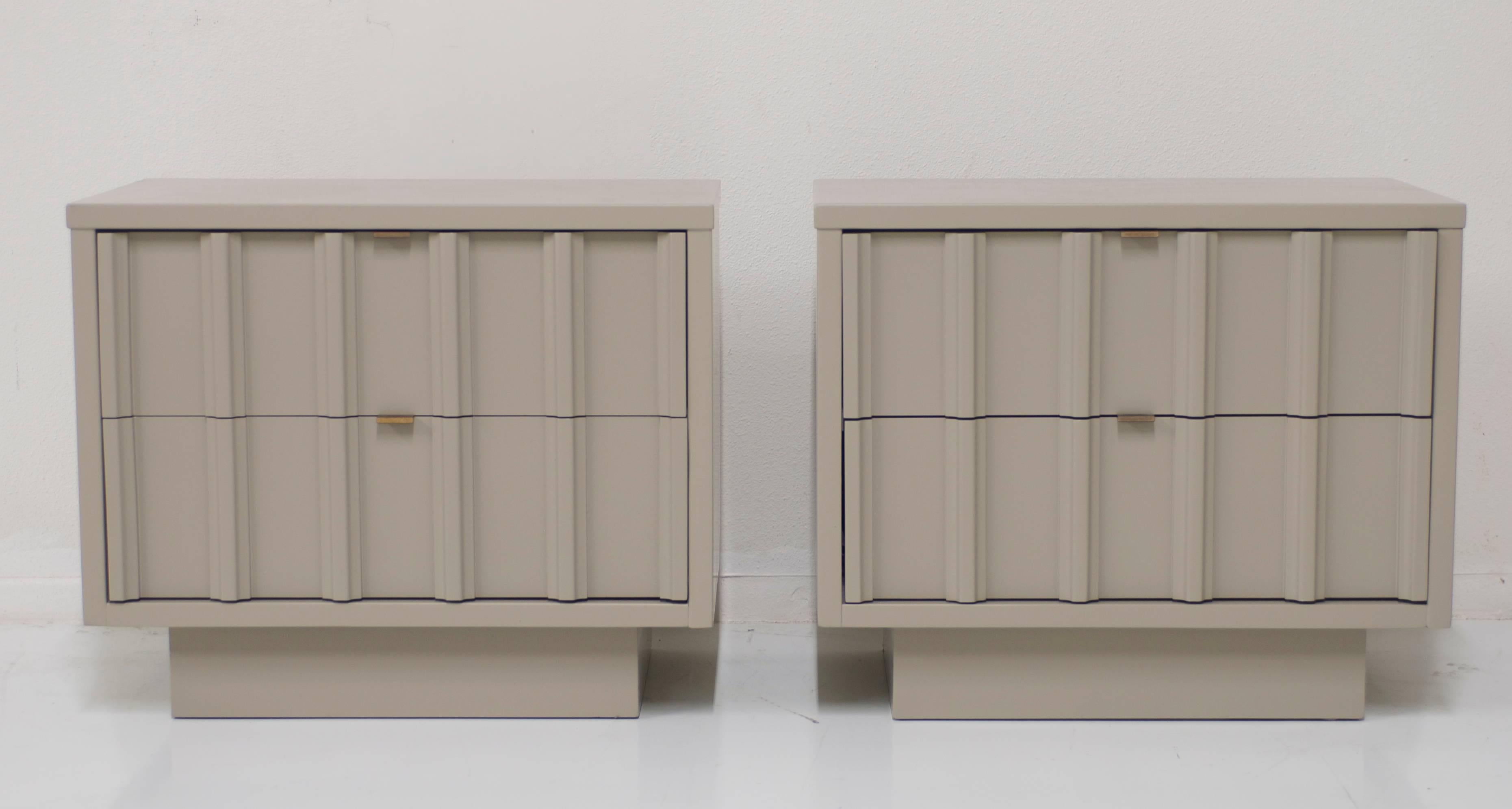 A pair of vintage nightstands that have been refinished in a dove gray taupe finish. The cabinets have two drawers each fitted with the original antique brass pulls.
  