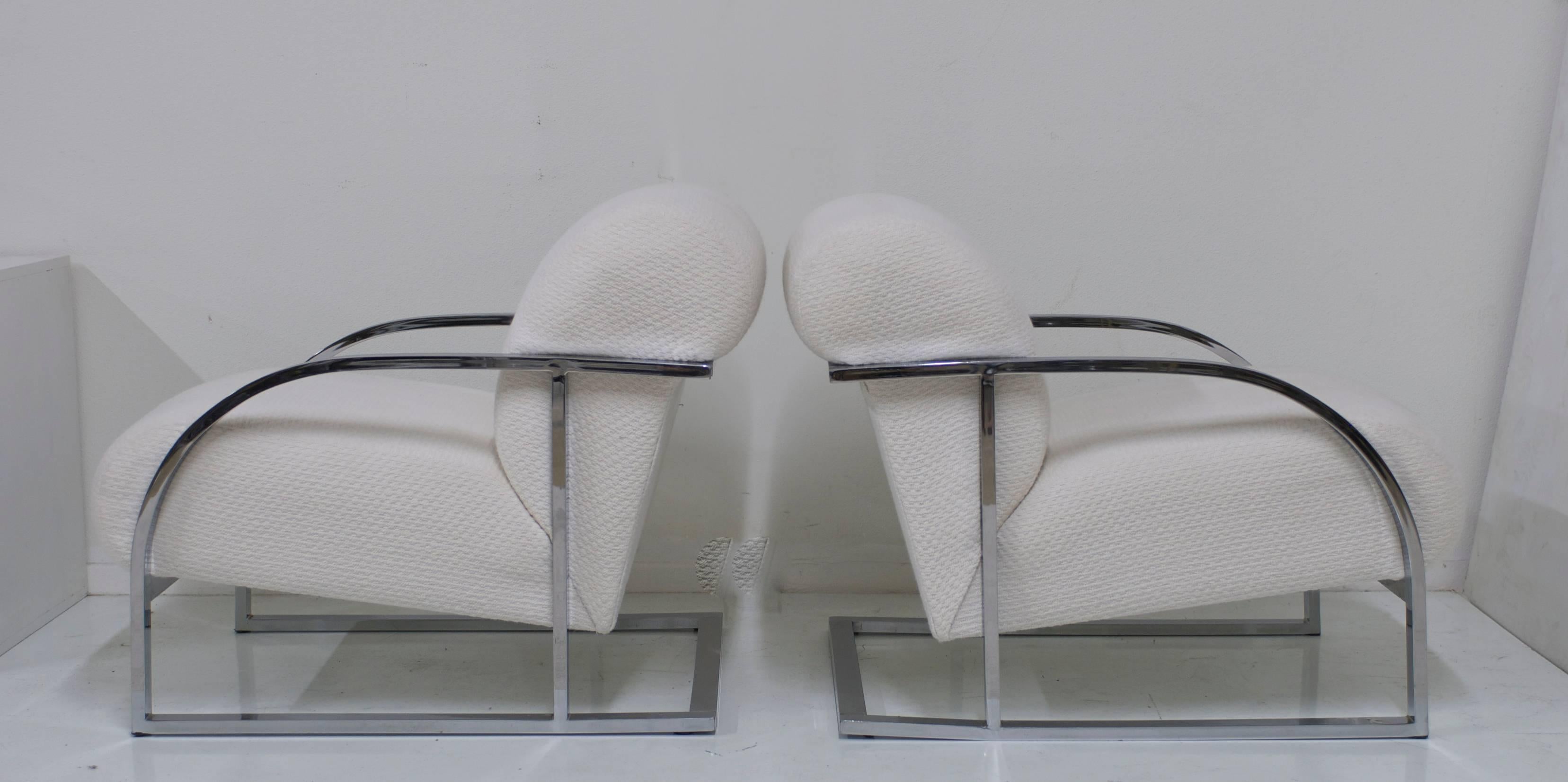 Attributed to Milo Baughman this pair of generously scaled and very comfortable pair of lounge chairs have an elegant curve to the arm. The frame is made of polished chrome. The upholstery is an ivory chenille which has been re-upholstered in the