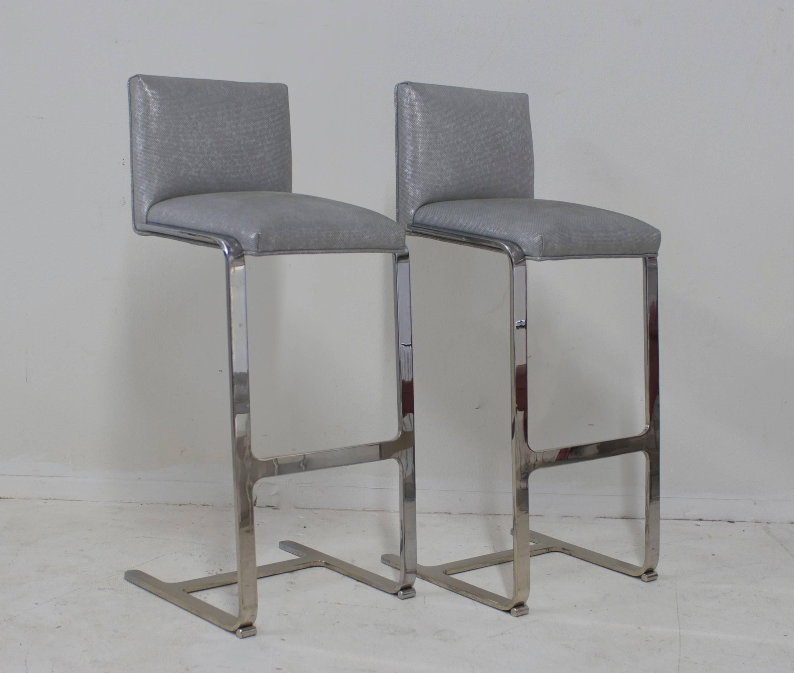Set of two barstools with backs that have been freshly upholstered in a soft silver leather with an iridescent sheen to it. The bar stools are cantilevered and nice and heavy.
