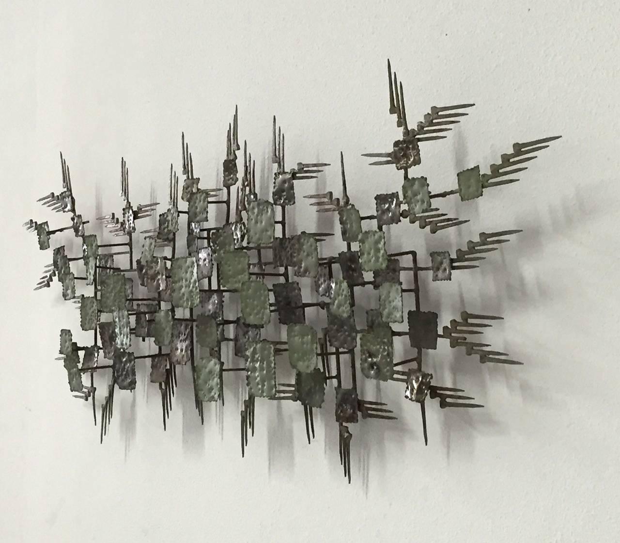 This hand made abstract mid-century modern metal wall sculpture has a nice oxidized soft sage green color to it. 
It can be hung vertically or horizontally.  It is signed but the signature is illegible.

 