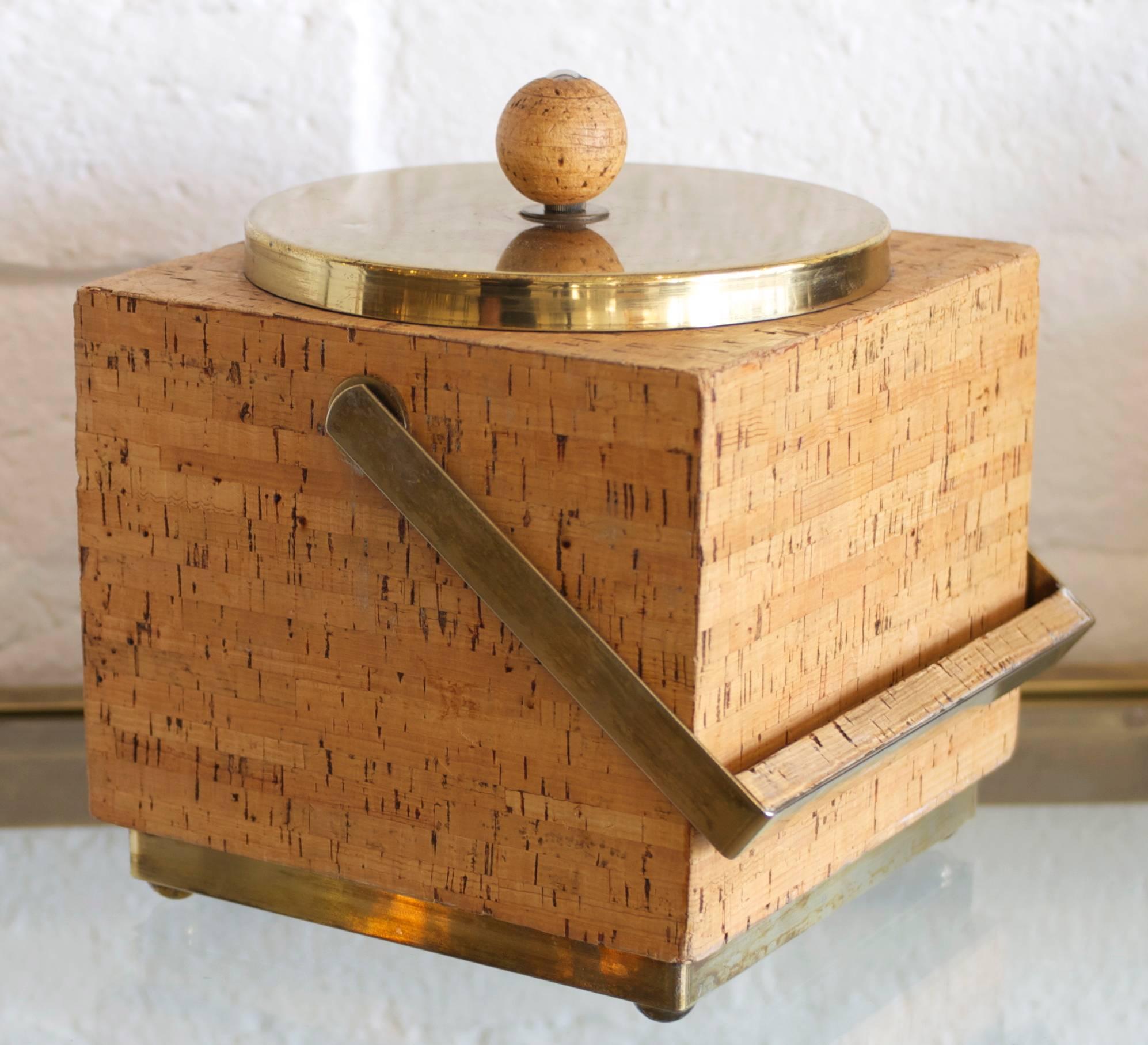 A square vintage Ice bucket made of stacked cork and brass with a drop handle. 
The base, lid and handle all are of brass and the round lid has a charming round 
cork knob.
      