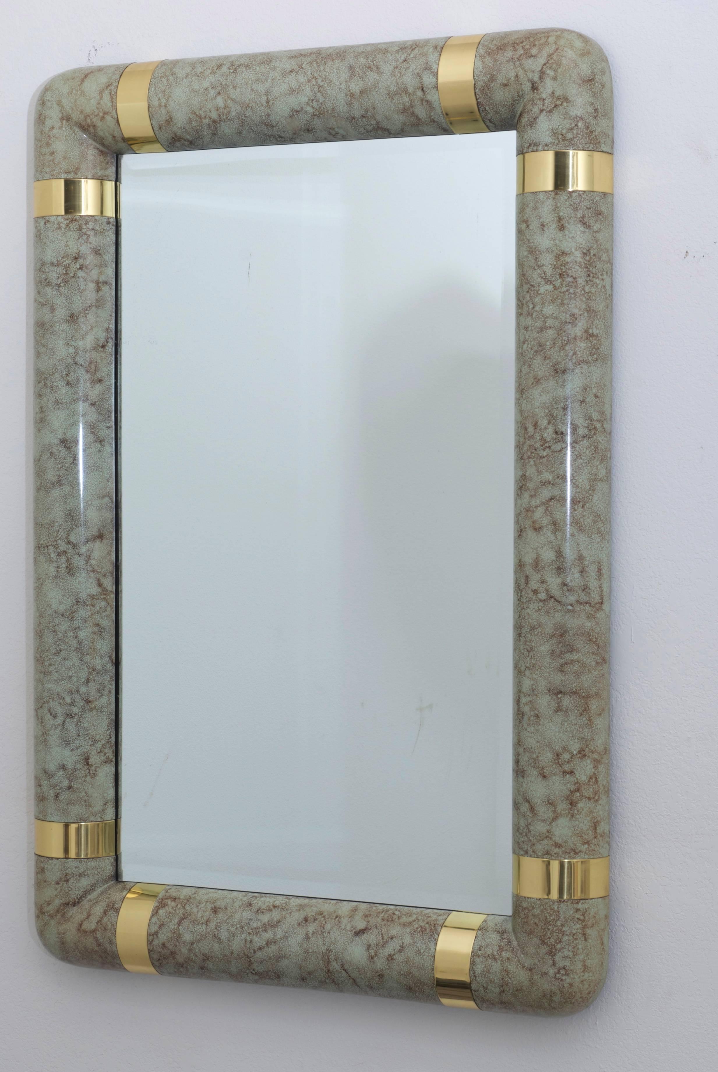 A heavy Karl Springer style mirror with a faux parchment veneer with brass details at the corners.
There are four mounting clips on the back so that it can be hung either vertically or horizontally.