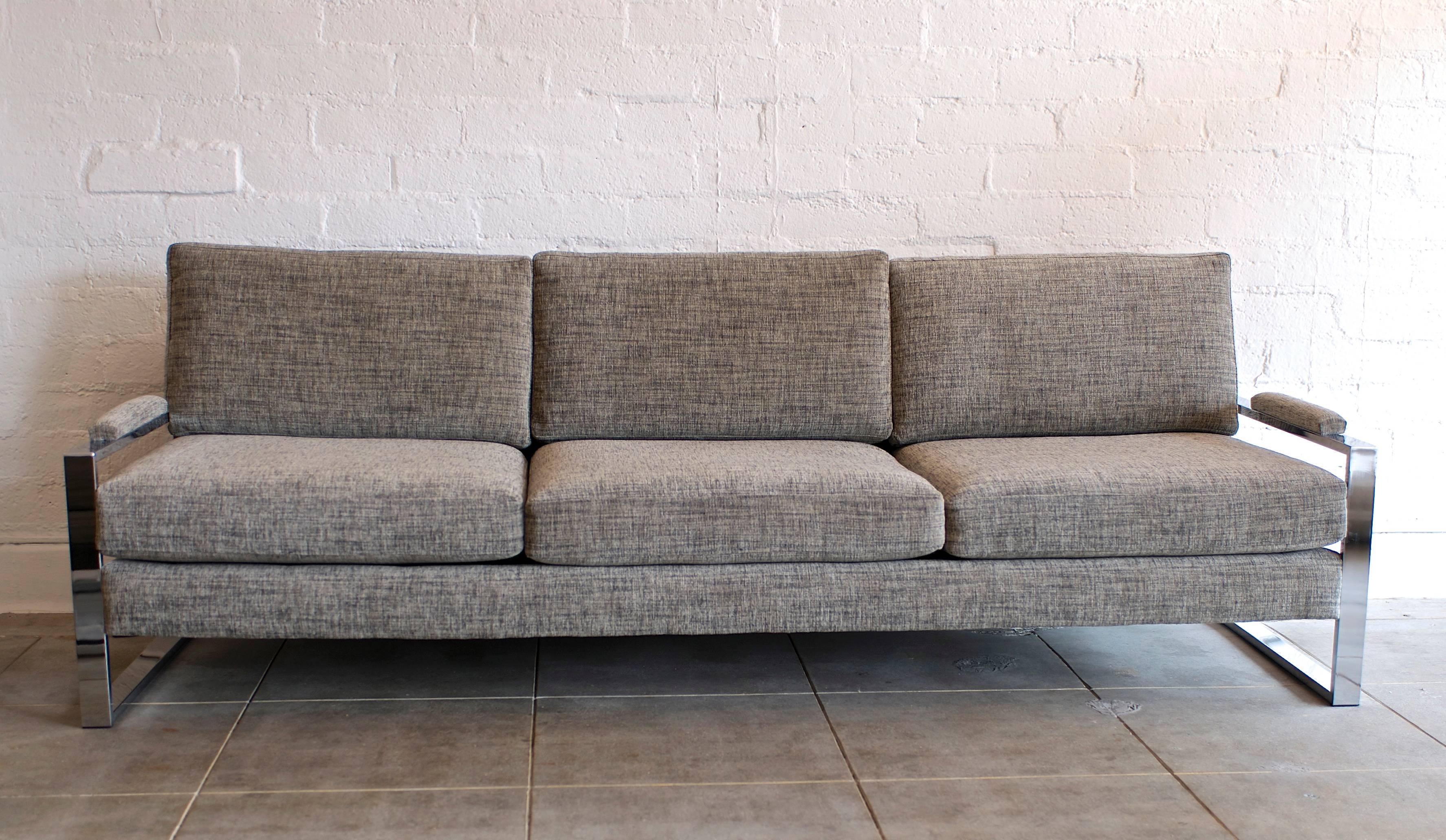 This handsome low slung Milo Baughman seating group is comprised of a three seat couch and a lounge chair. They have been completely redone with new foam and reupholstered in a handsome pewter grey weave much like a mens suiting fabric. The side