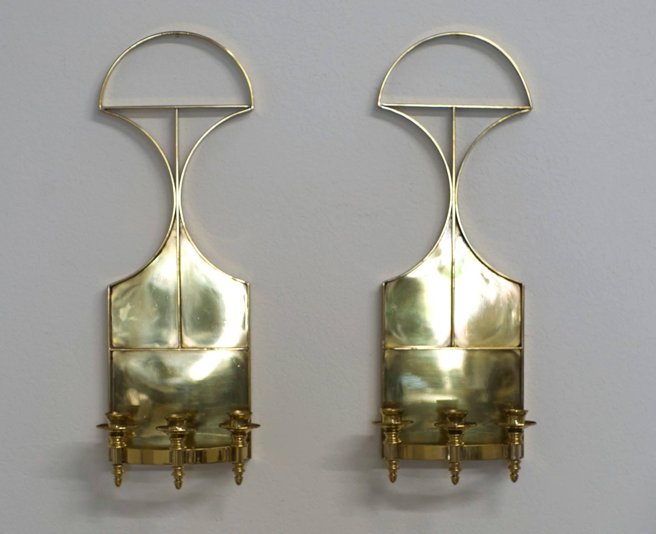 Tommi Parzinger style pair of Mid-Century solid brass wall sconces.
This elegant pair of sconces is solid and fully finished on the back.
Each sconce has three candle holders and will reflect a nice warm glow when lit.
