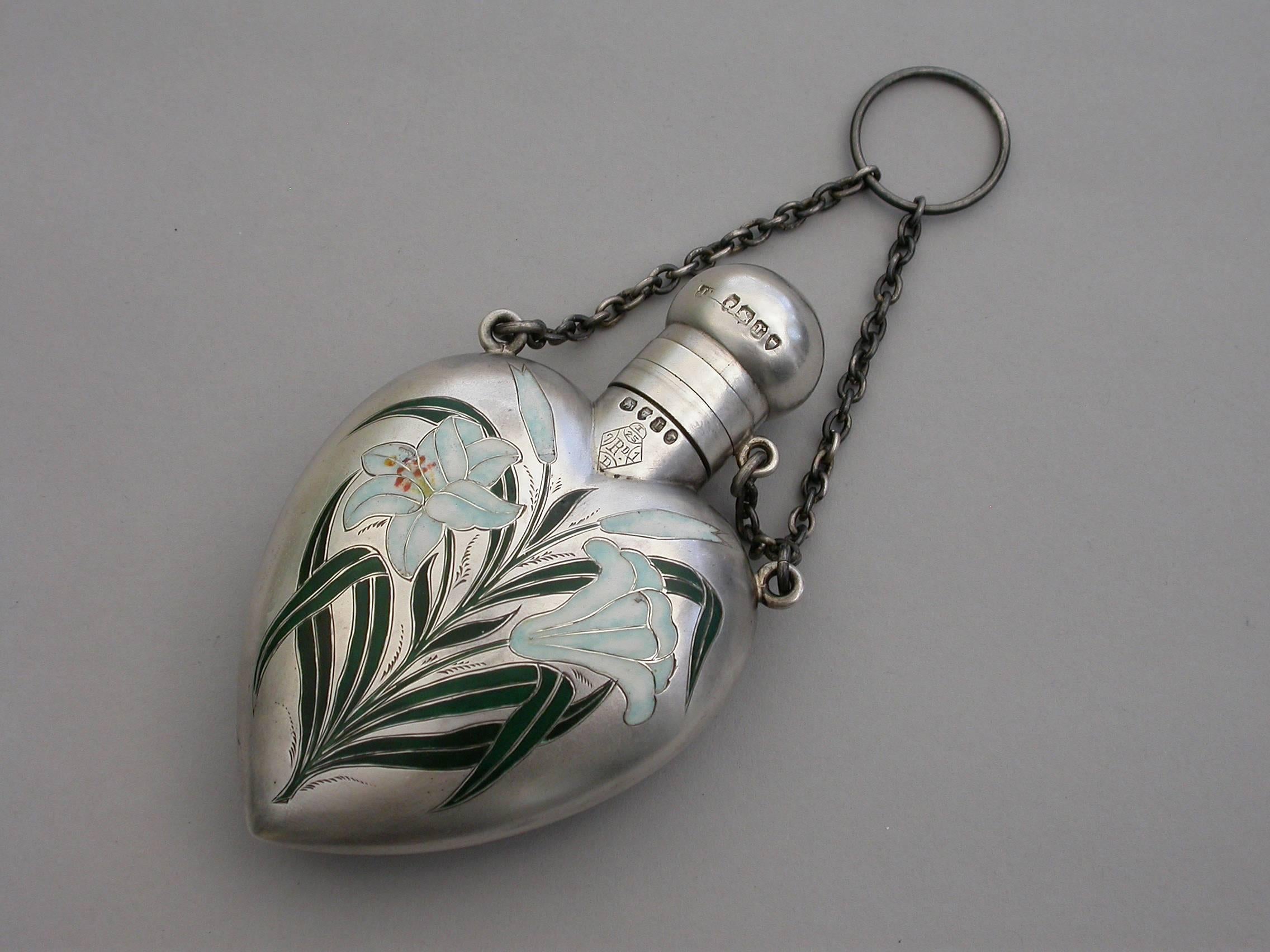 A very fine quality Victorian heart shaped cased silver and enamel Scent Flask with attached suspension ring and chains to secure the screw-off domed cover, the face enamelled with Lily flowers and stems, the reverse engraved with contemporary