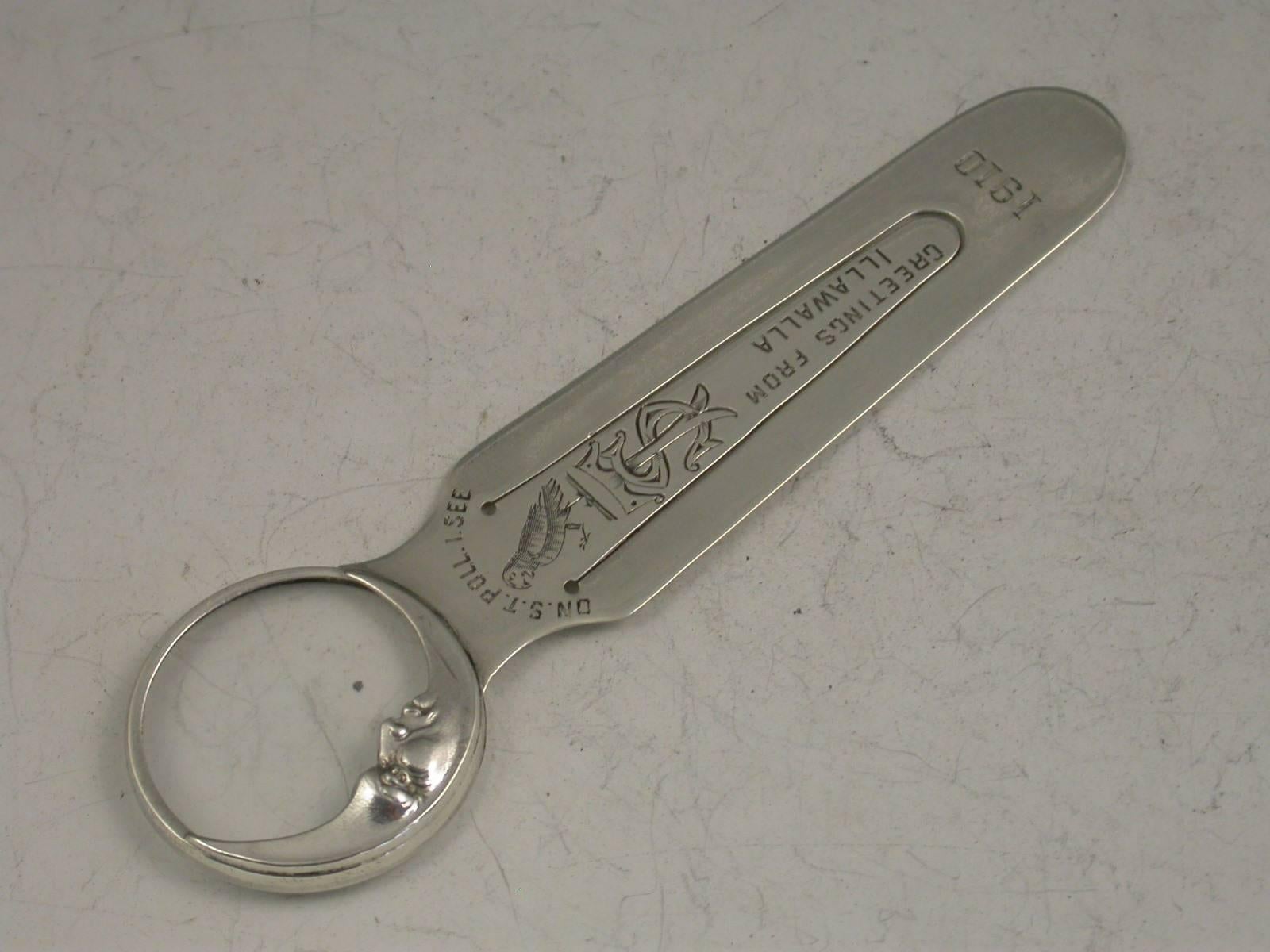 A rare Edwardian novelty silver bookmark, the terminal formed from a magnifying glass with a border depicting a man in a crescent moon. The blade with an interesting inscription - greetings from Illawalla and engraved with a parrot and the legend