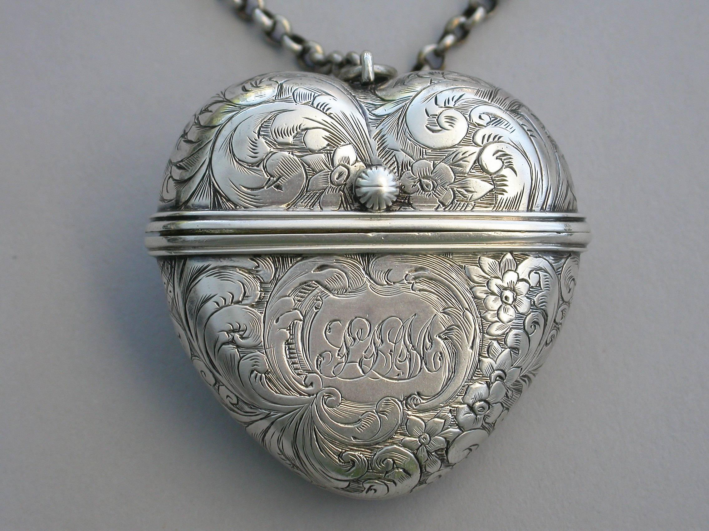 A rare Victorian silver Vinaigrette made in the form of a heart, with attached suspension ring and chain, the body all-over engraved with scrolling leaves and flowers, the design repeated on the internal pierced silver gilt grille. A shaped