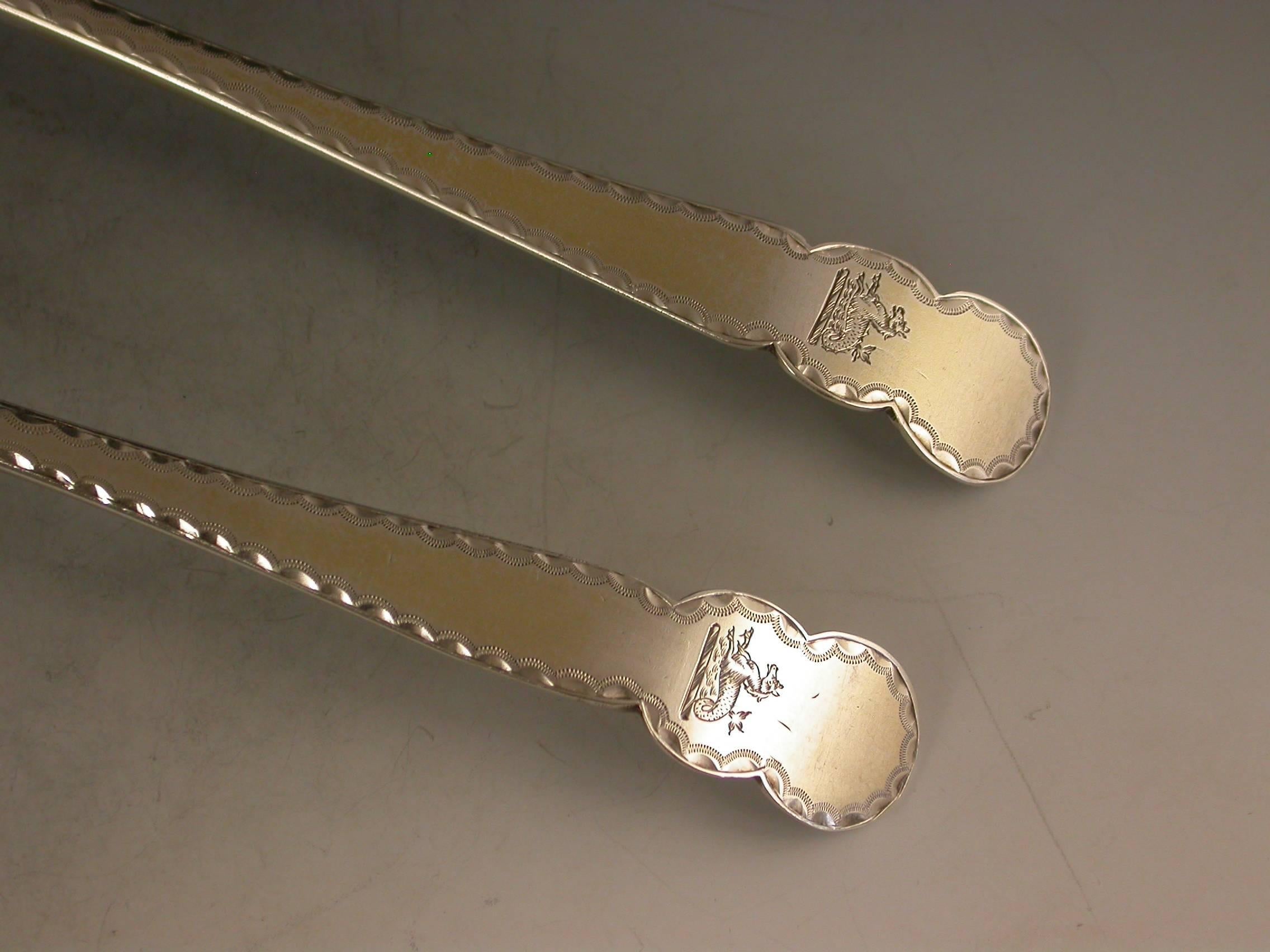 A very unusual pair of George III silver gilt table spoons with fluted bowls, the shaped Old English type handles with bright-cut engraved borders and of a pattern not previously encountered. Engraved with contemporary crests.

By Thomas & William