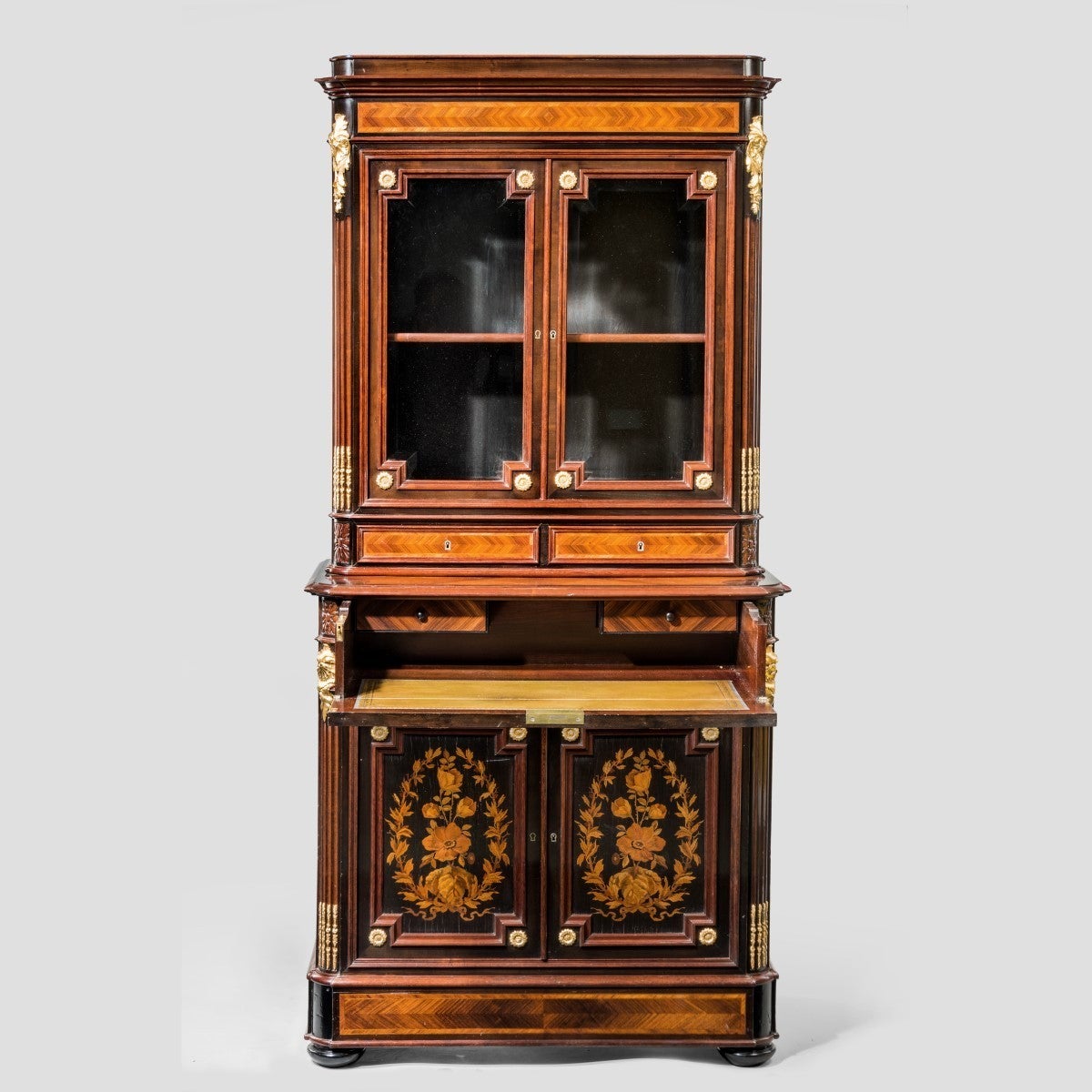 A superb quality Napoleon III kingwood bookcase of unusually small proportions, with a glazed upper section, a fitted secretaire drawer and a cupboard below enclosing an adjustable shelf, decorated throughout with striking quarter veneers, ormolu