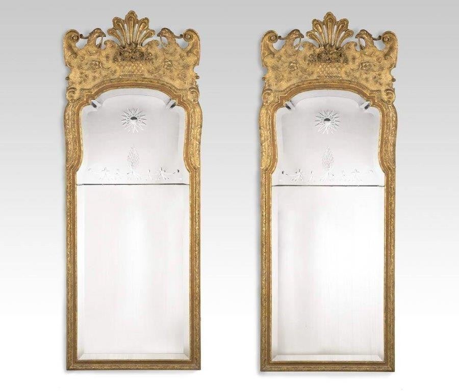 A pair of Victorian giltwood mirrors, the frames carved with baskets of fruit flanked by eagles and enclosing shaped and bright cut plates in George l style.
