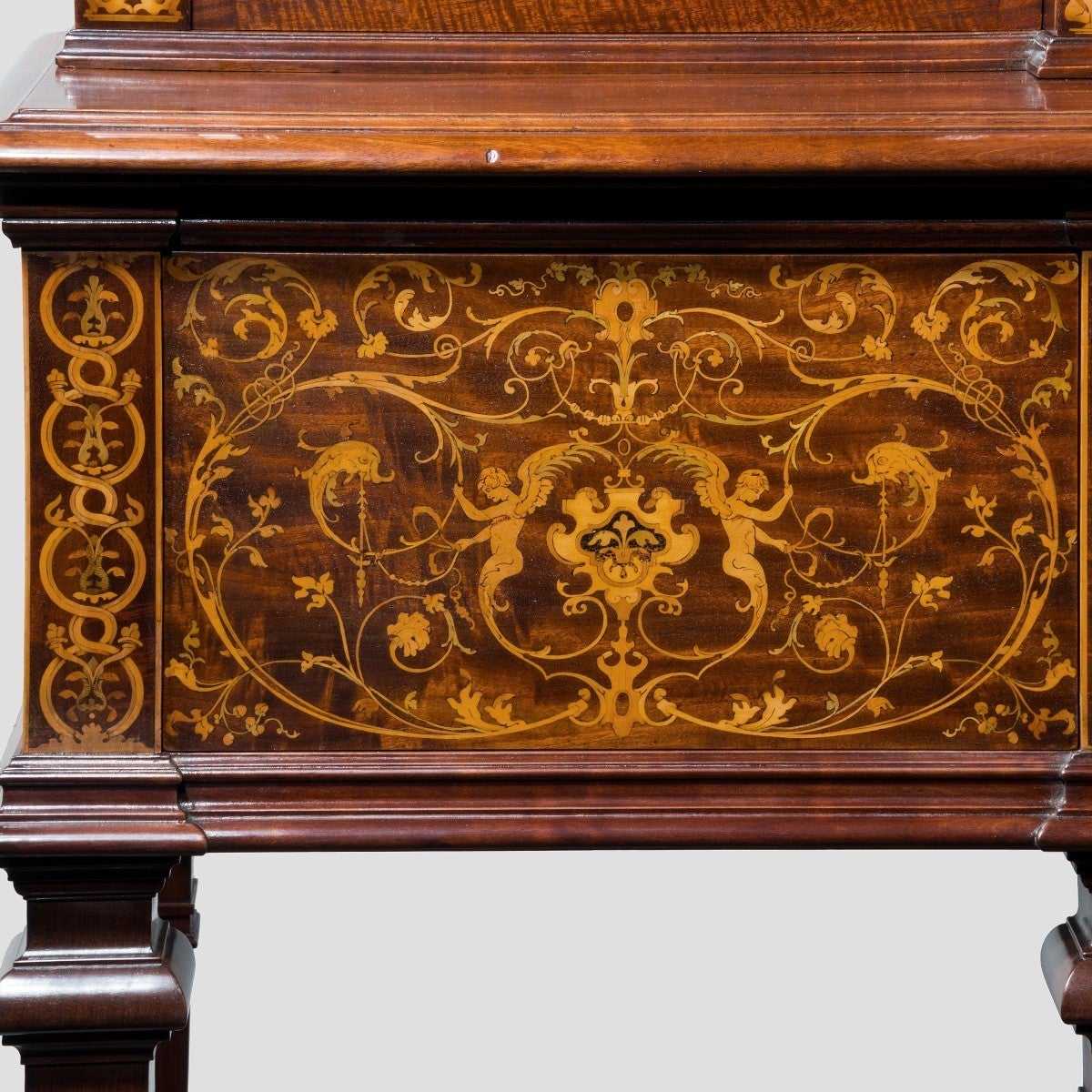Superb late Victorian mahogany side cabinet with satinwood and box book inlays depicting cherubs and stylized dolphins amongst a floral scene. Three secret drawers to the frieze and three glazed door to the top. Attributed to Collinson and Lock.